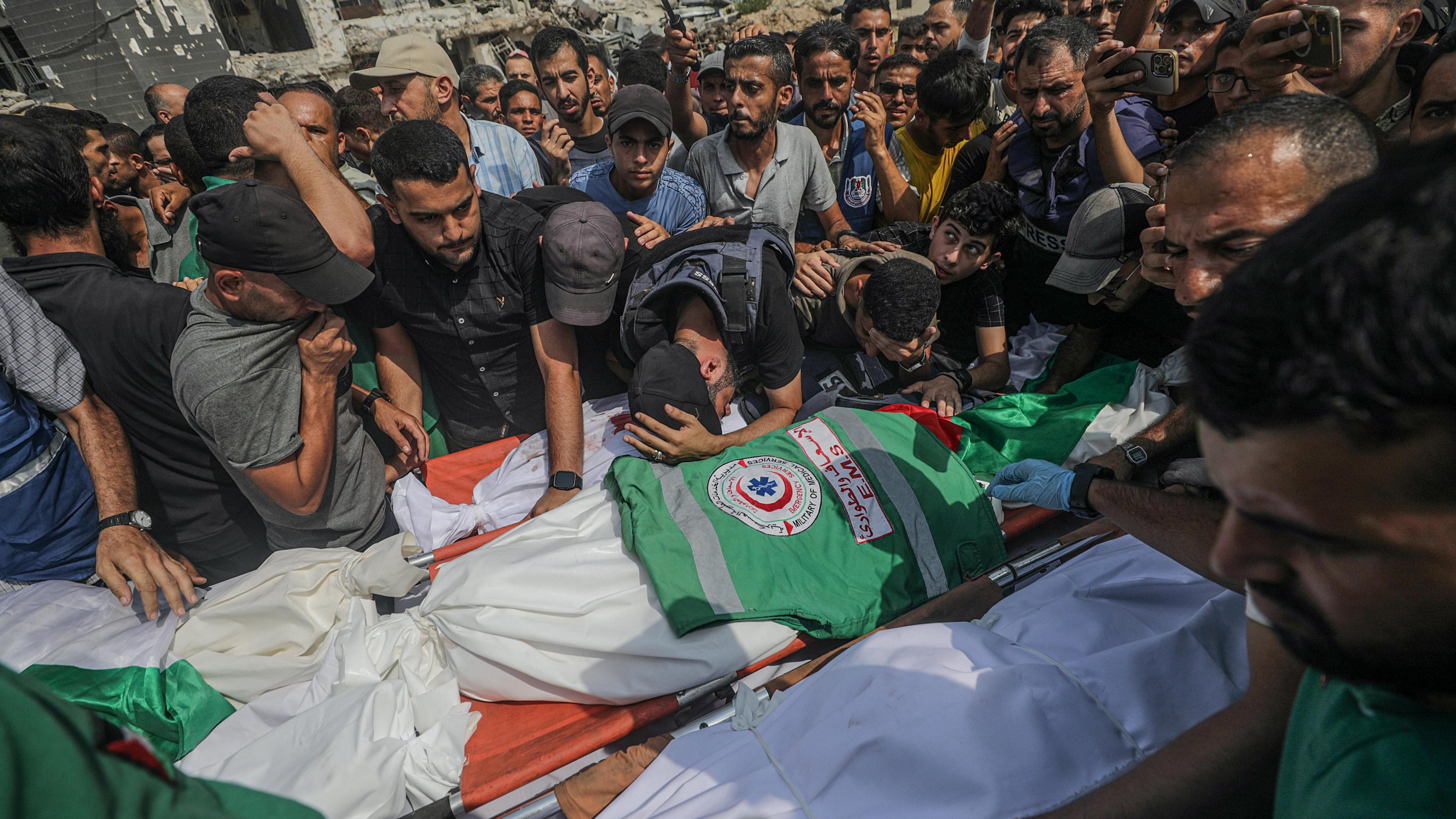 A crowd of men gather around the shroud covered bodies people who were killed during Israel' stargeted attack on Gaza City on Sunday night.