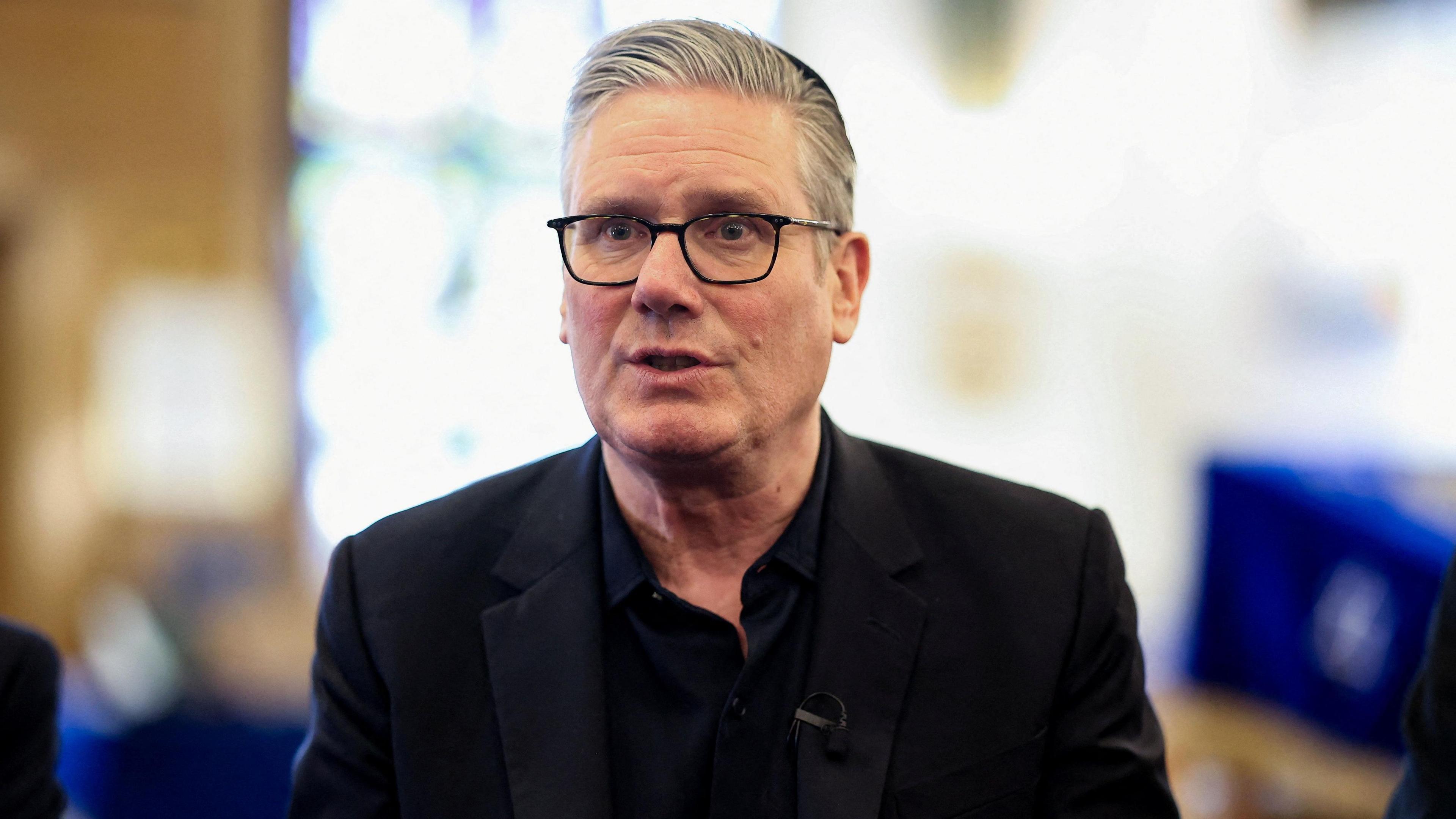 Keir Starmer wearing a black suit and black shirt