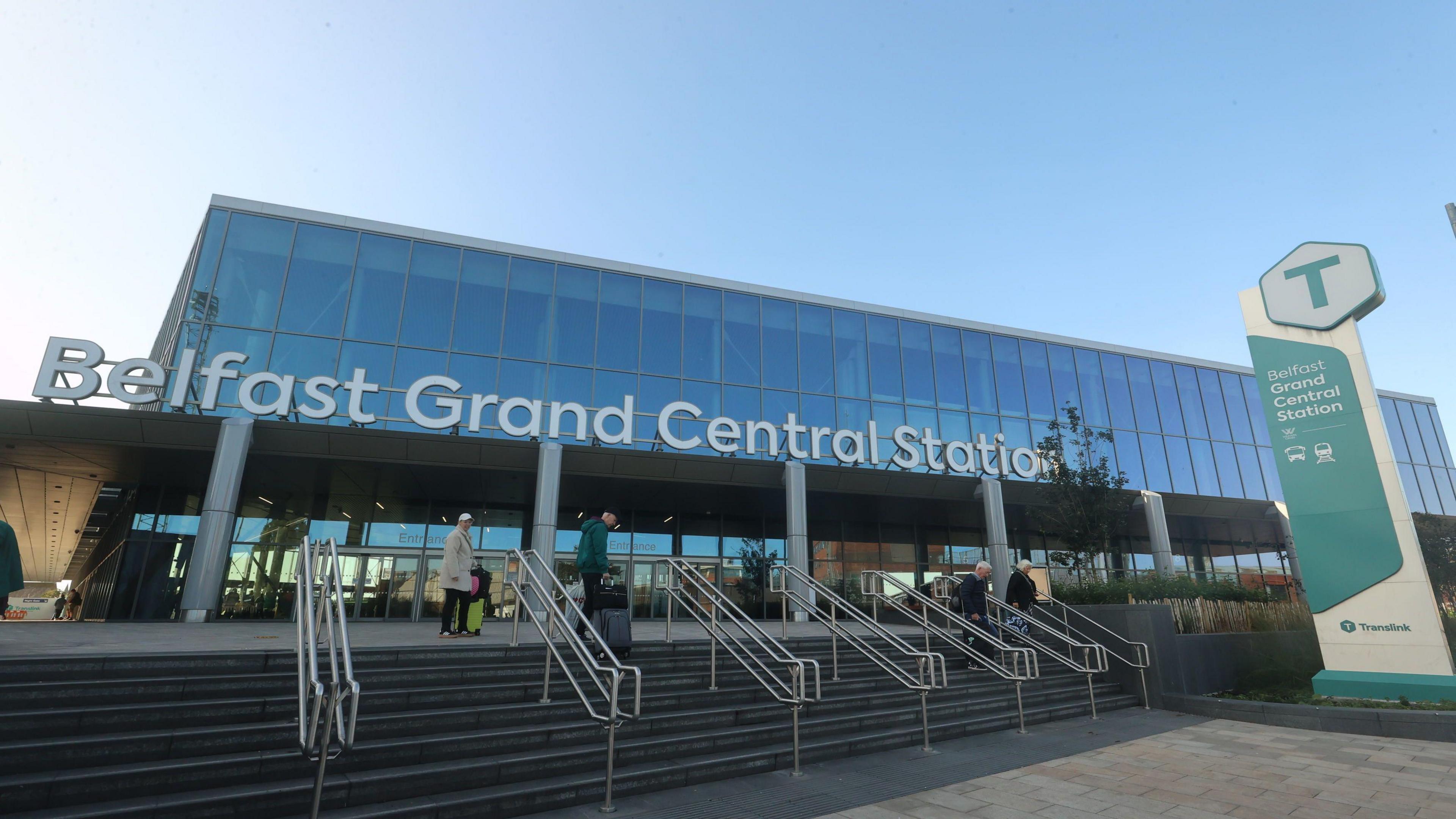 A glass building with large white letters saying Belfast Grand Central Station on the front.