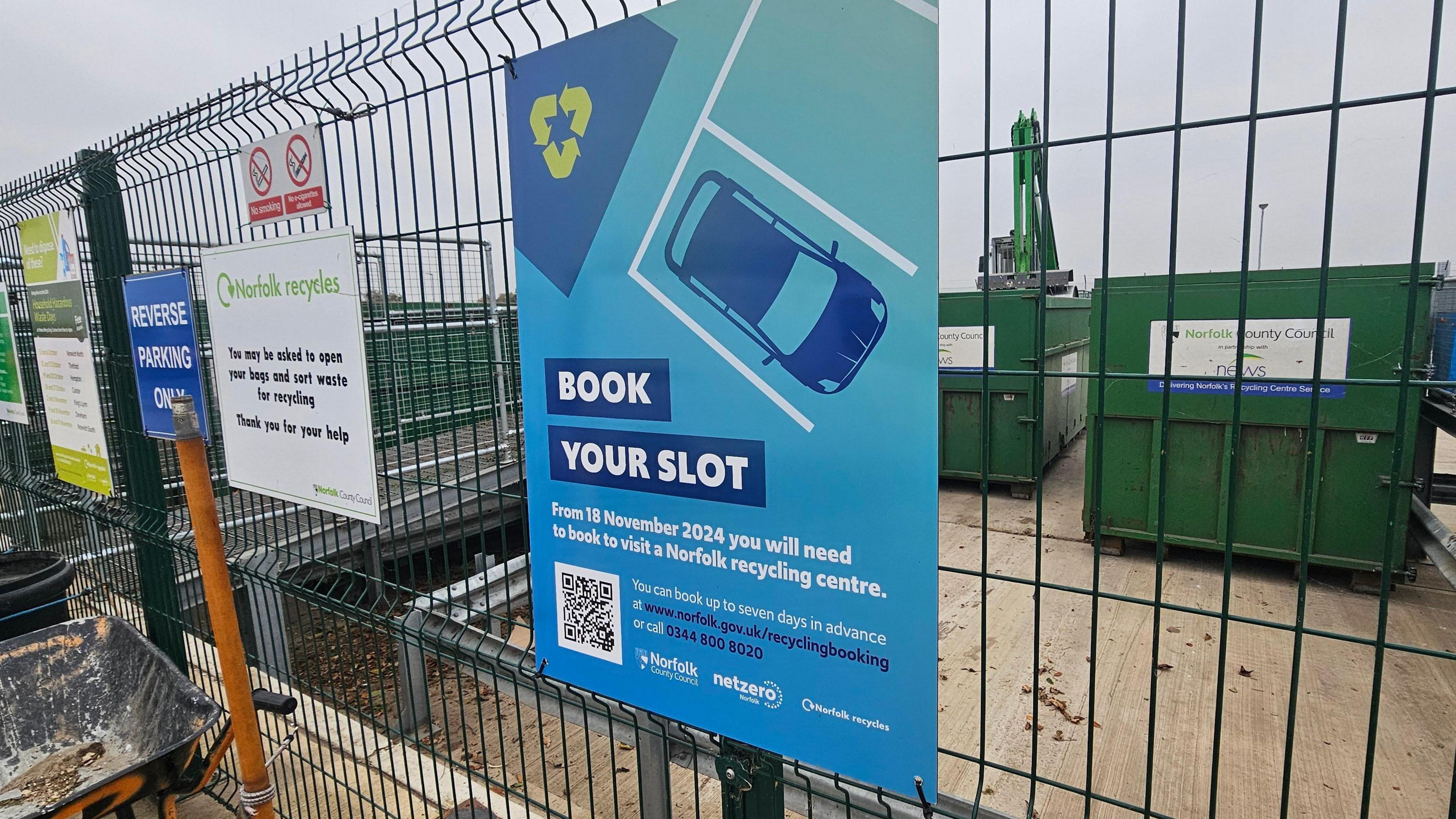 A mostly-blue sign at a recycling centre telling people 'book your slot'