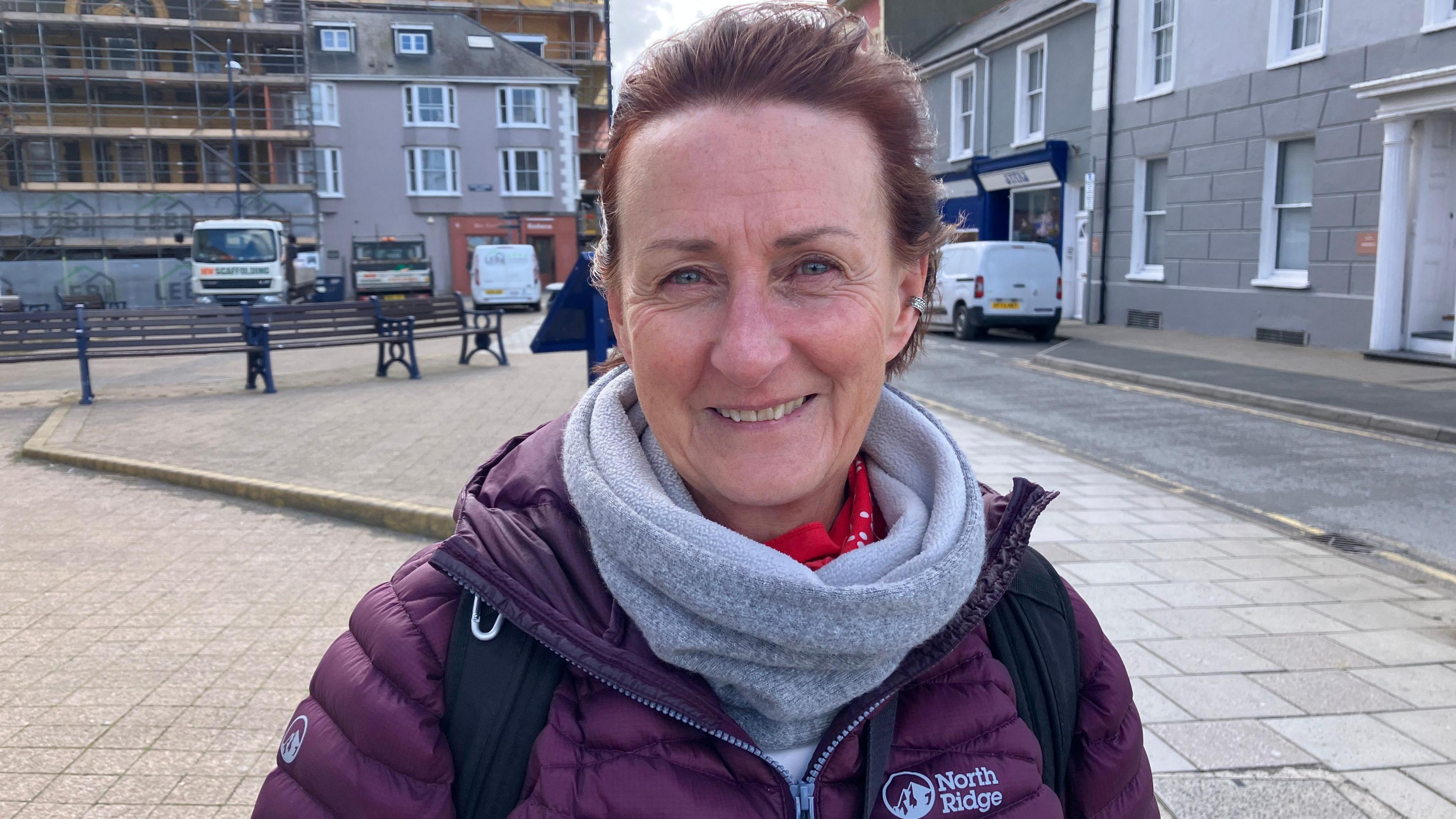 Llun o fenyw - Alison Warren - yn sefyll ar brom Aberystwyth gyda'i chefn at y dref. Mae ganddi wallt tywyll, sgarff lwyd a chot borffor.