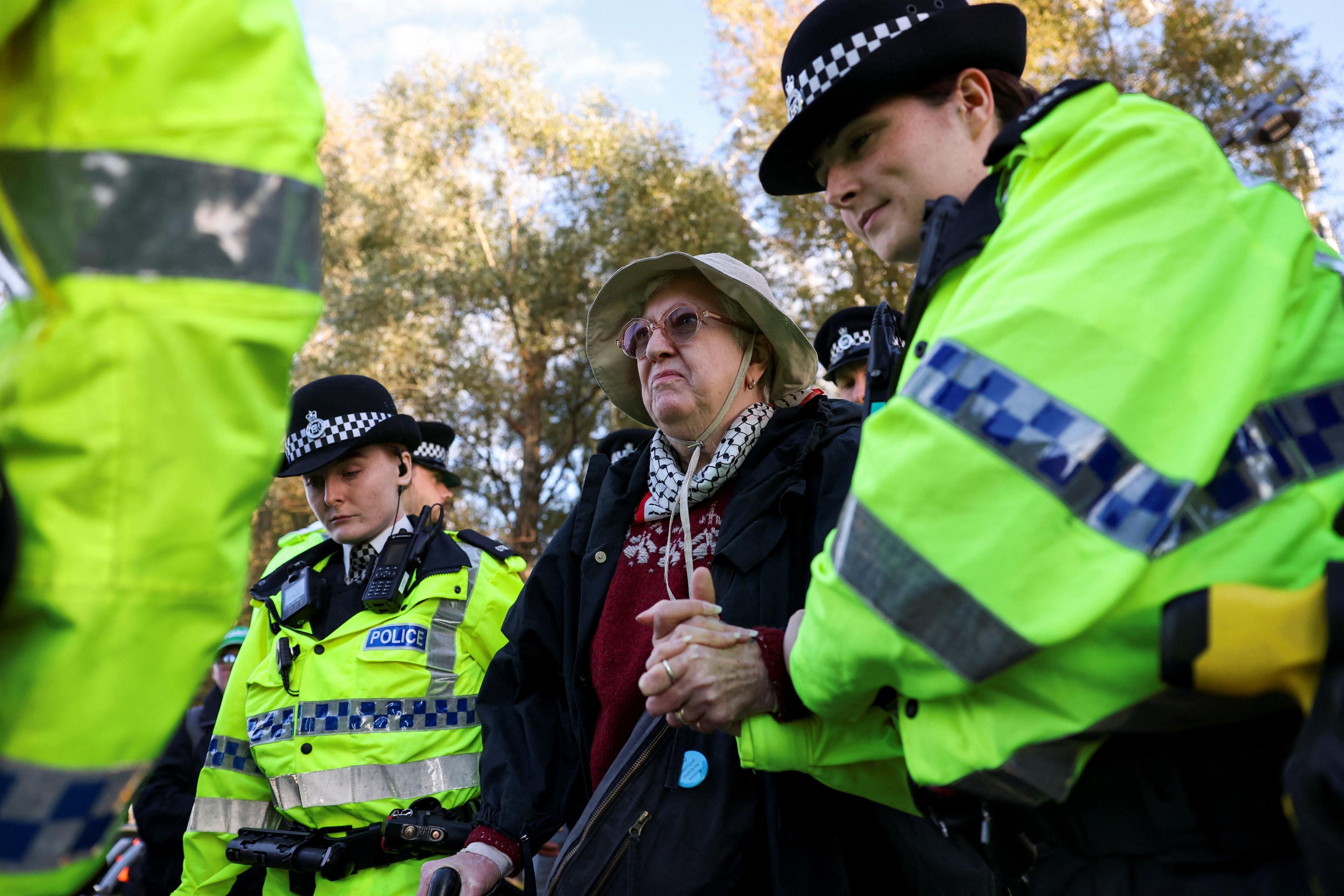 A woman is detained by police officers, during a 'Lift the Ban on Palestine Action' protest, organised by Defend our Juries