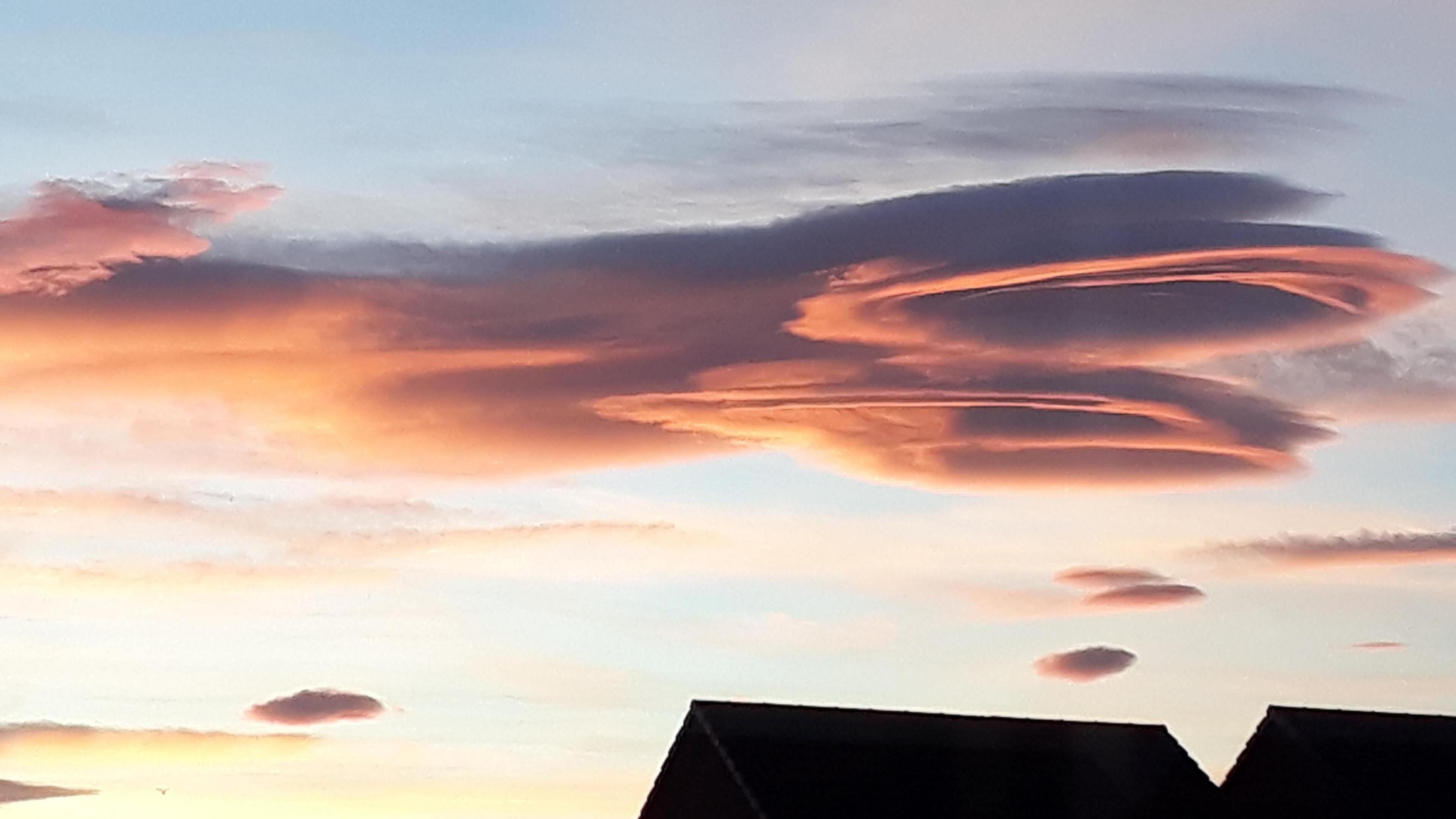 Layers of cloud above the silhouette of a roof top