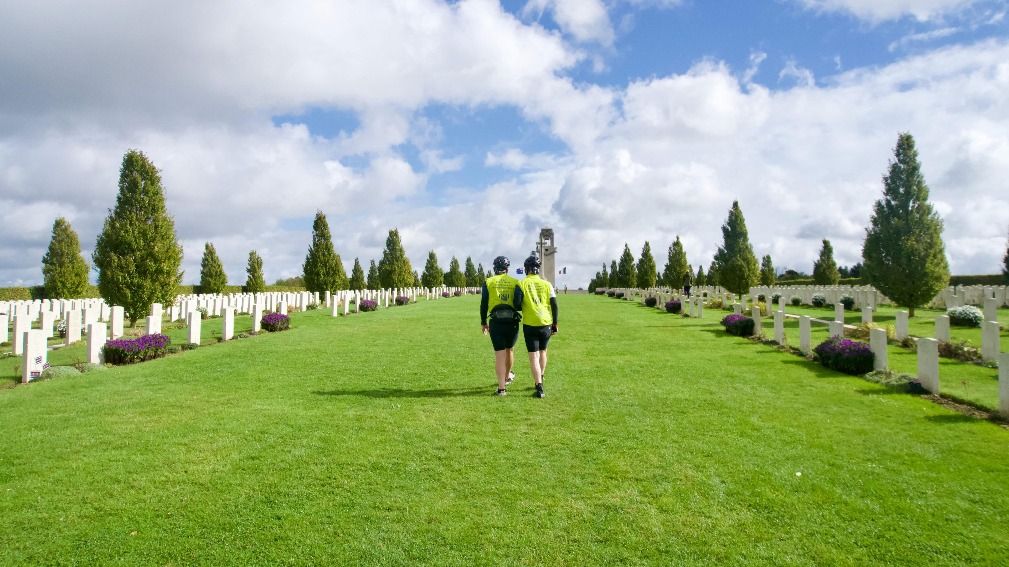 Two men walking together up a hill at a war cemetery