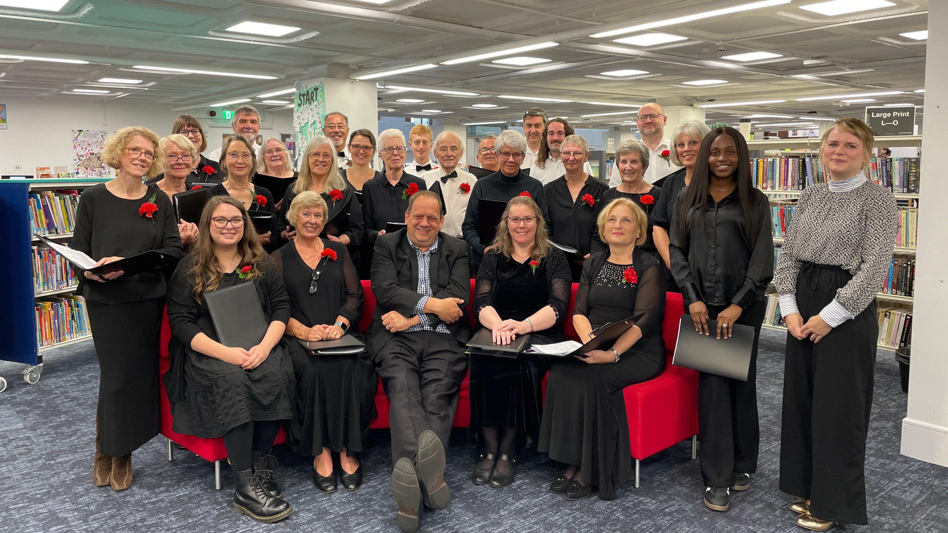 Redditch Choral Society sitting on the red sofa at Redditch Library with reporter Ben Sidwell