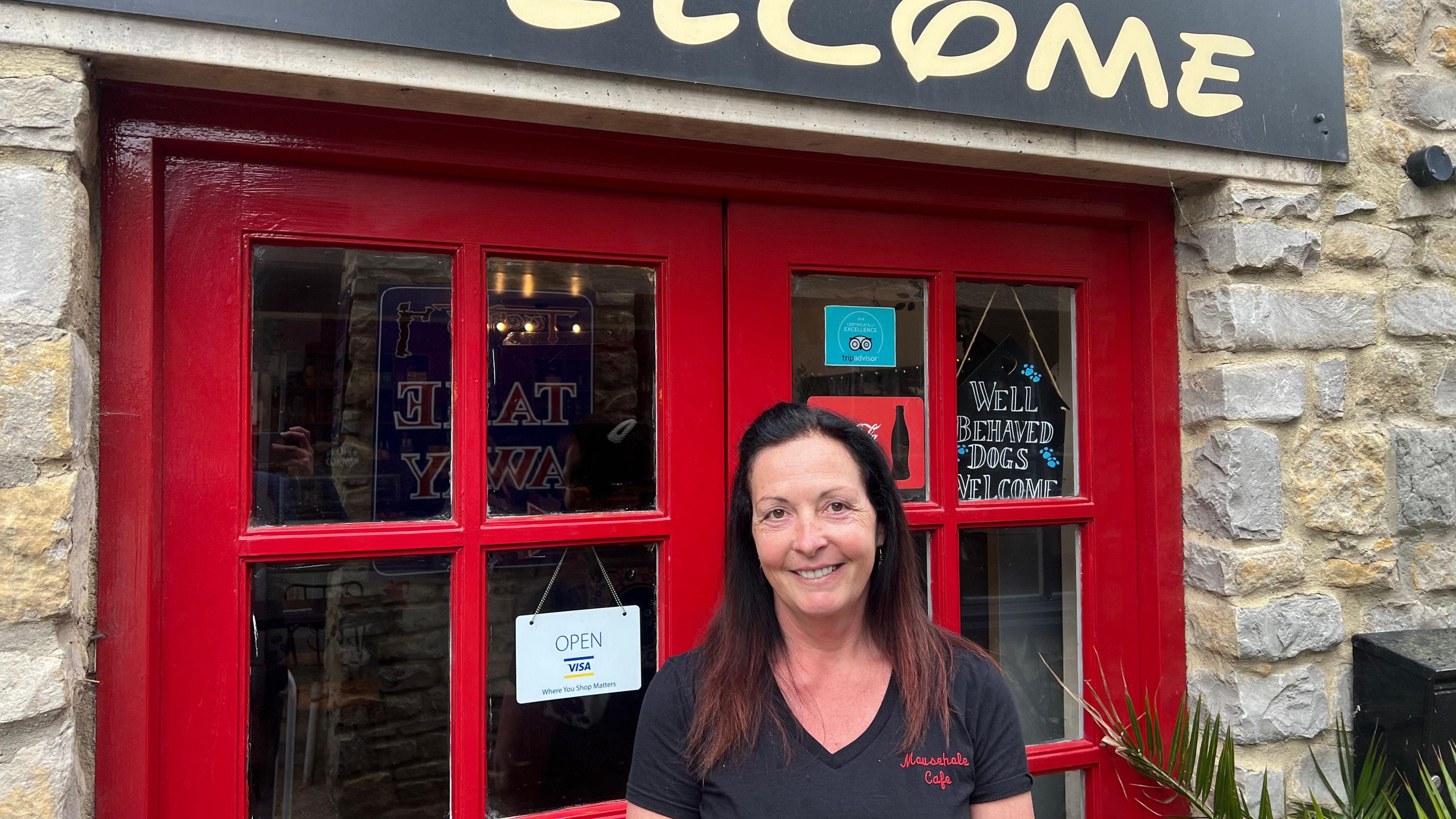 Women smiling looking at the camera outside café with sign saying' Mousehole Café'