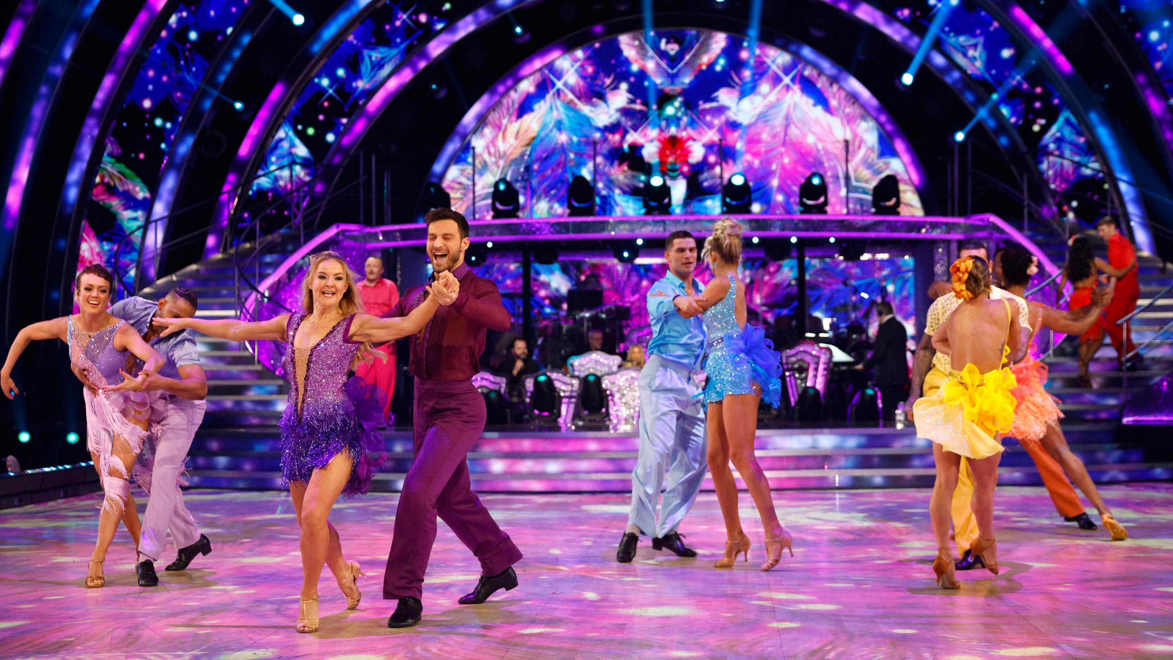 Dancers in sequins and sparkly outfits move on the Strictly Come Dancing set