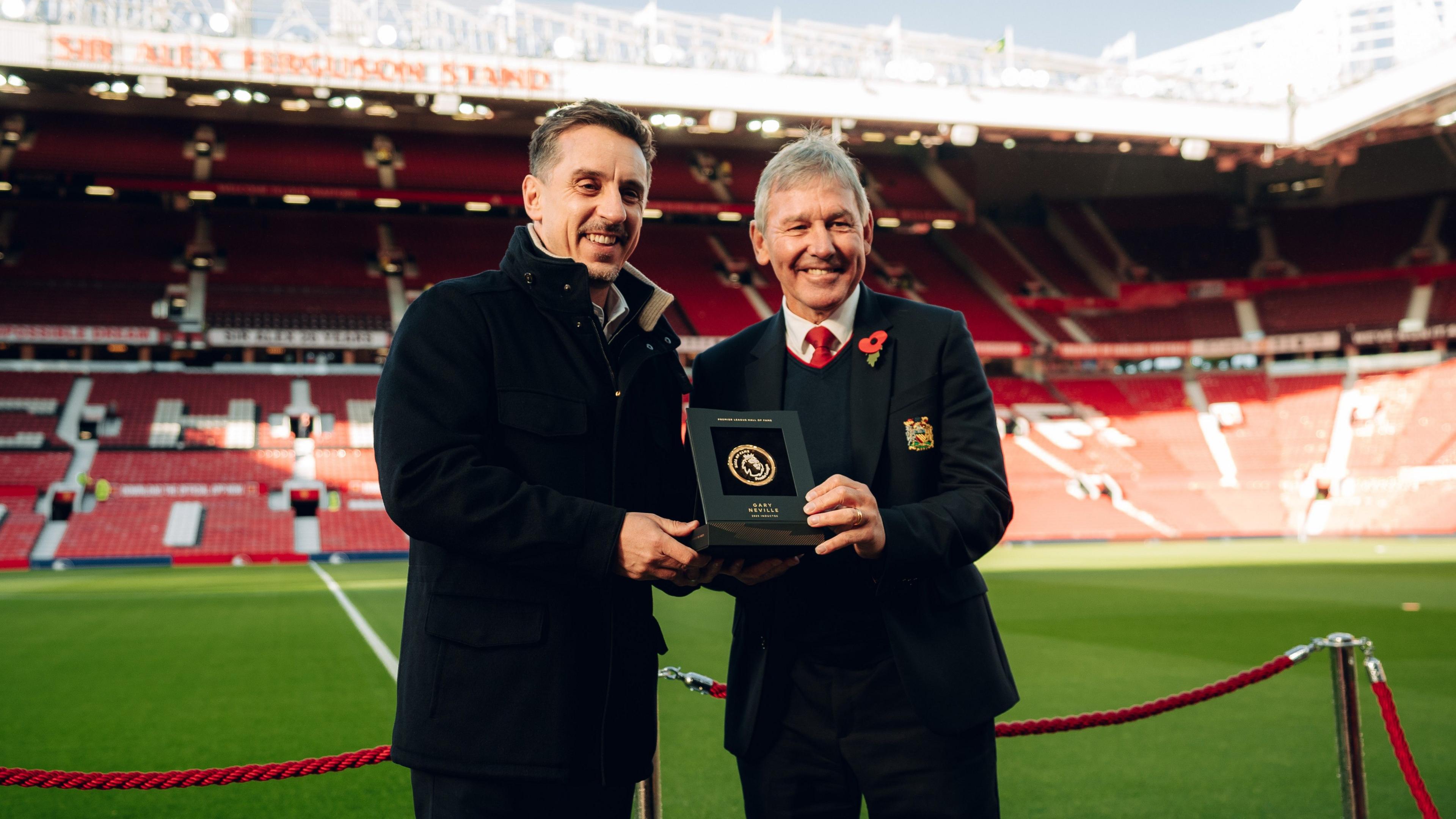 Gary Neville (left) and Bryan Robson (right) hold up a Premier League Hall of Fame medallion