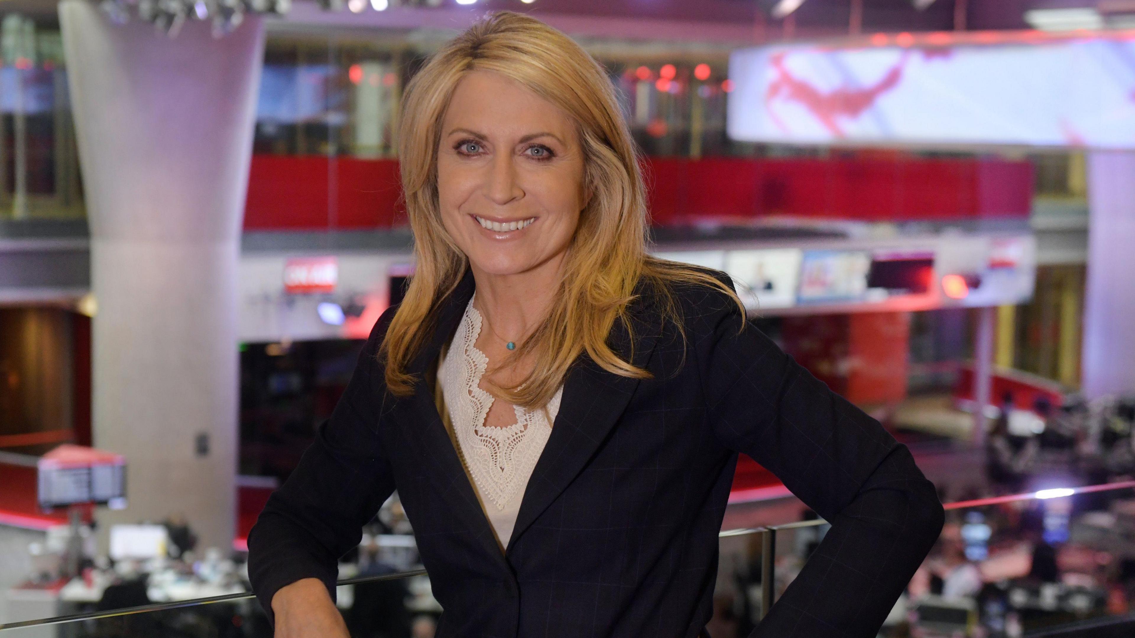 Deborah Turness leans on a rail above the BBC newsroom