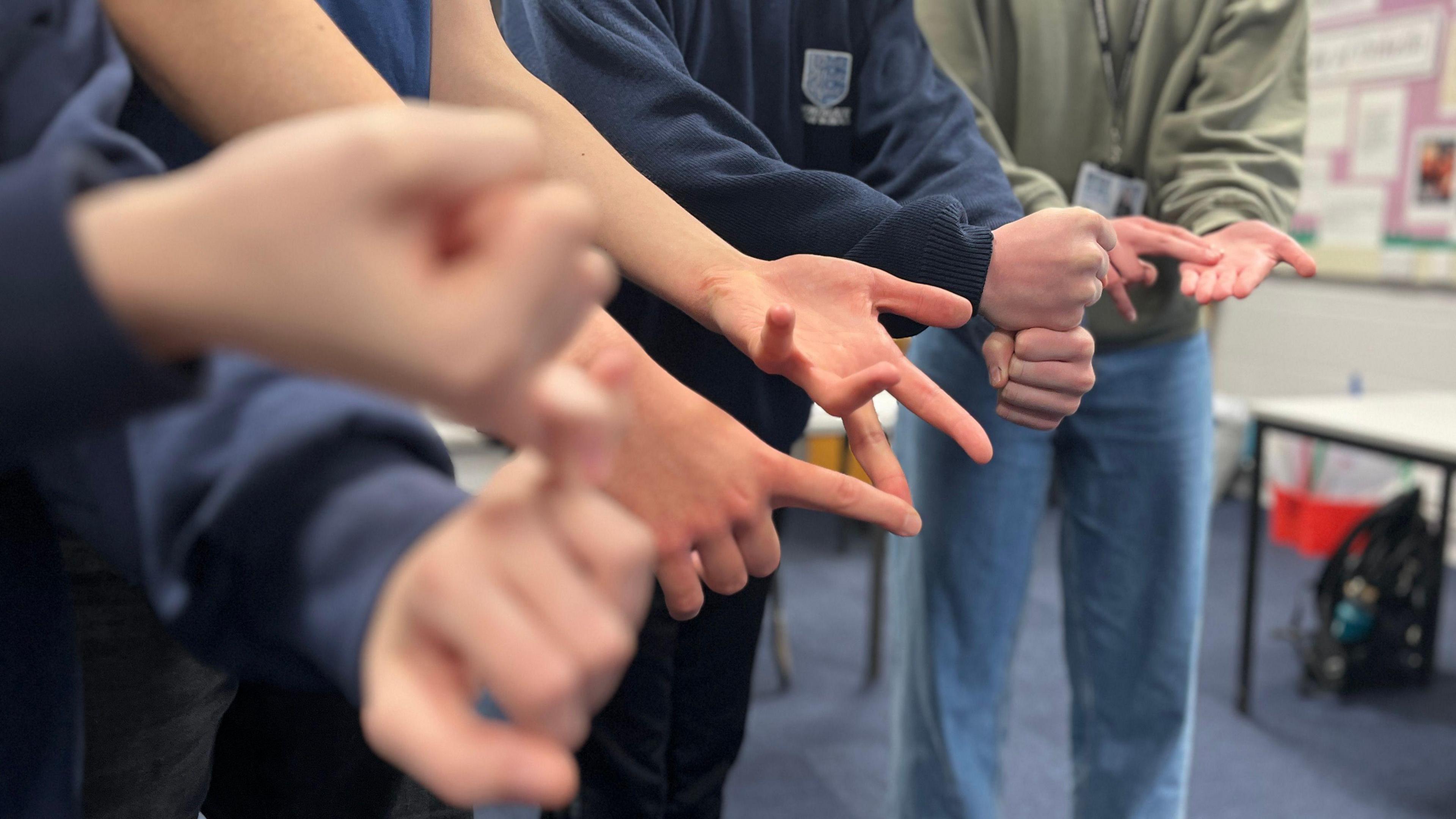 Four people's hands signing "S I G N"