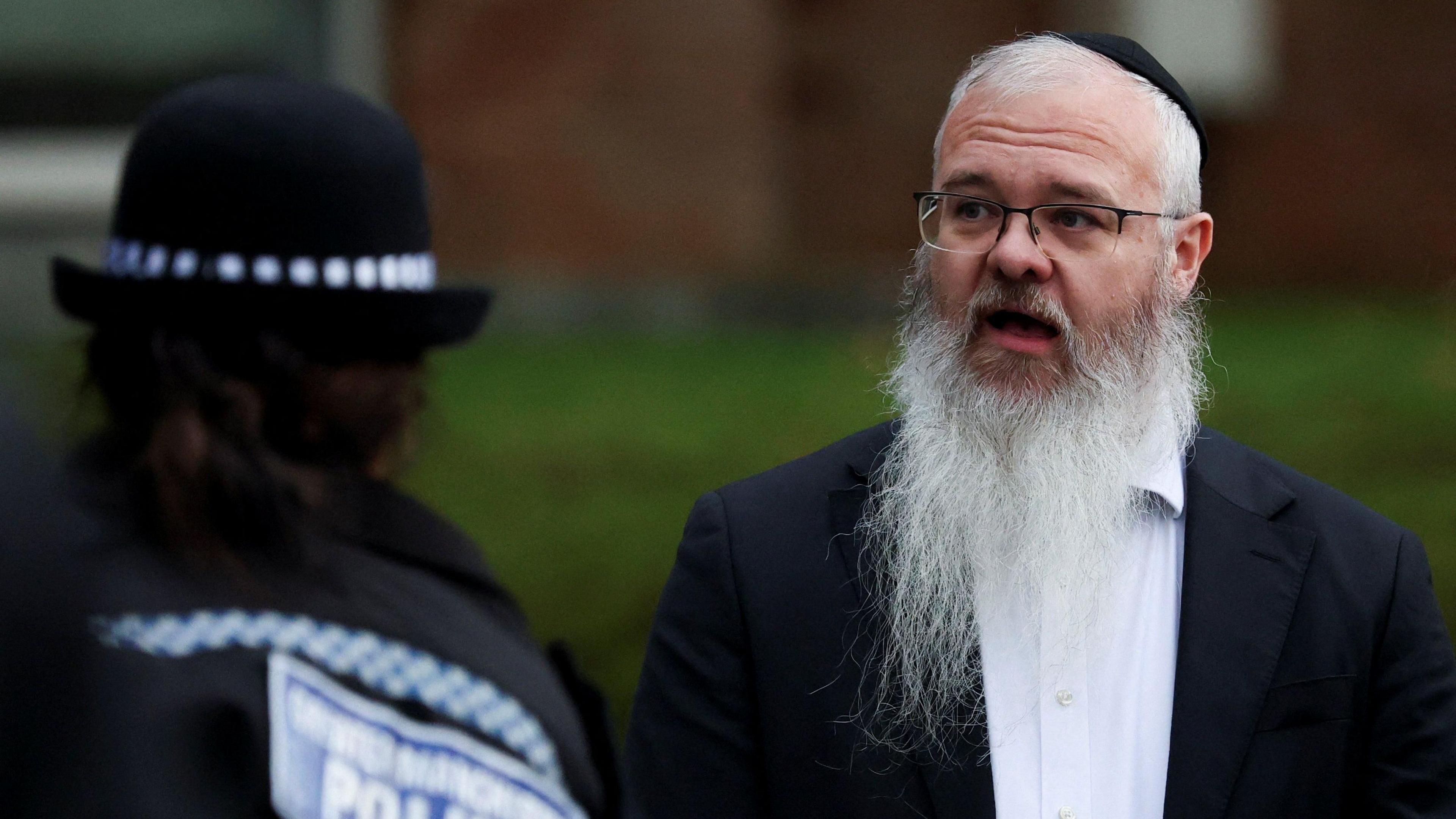 Rabbi Daniel Walker talking to a police officer at the scene of the attack