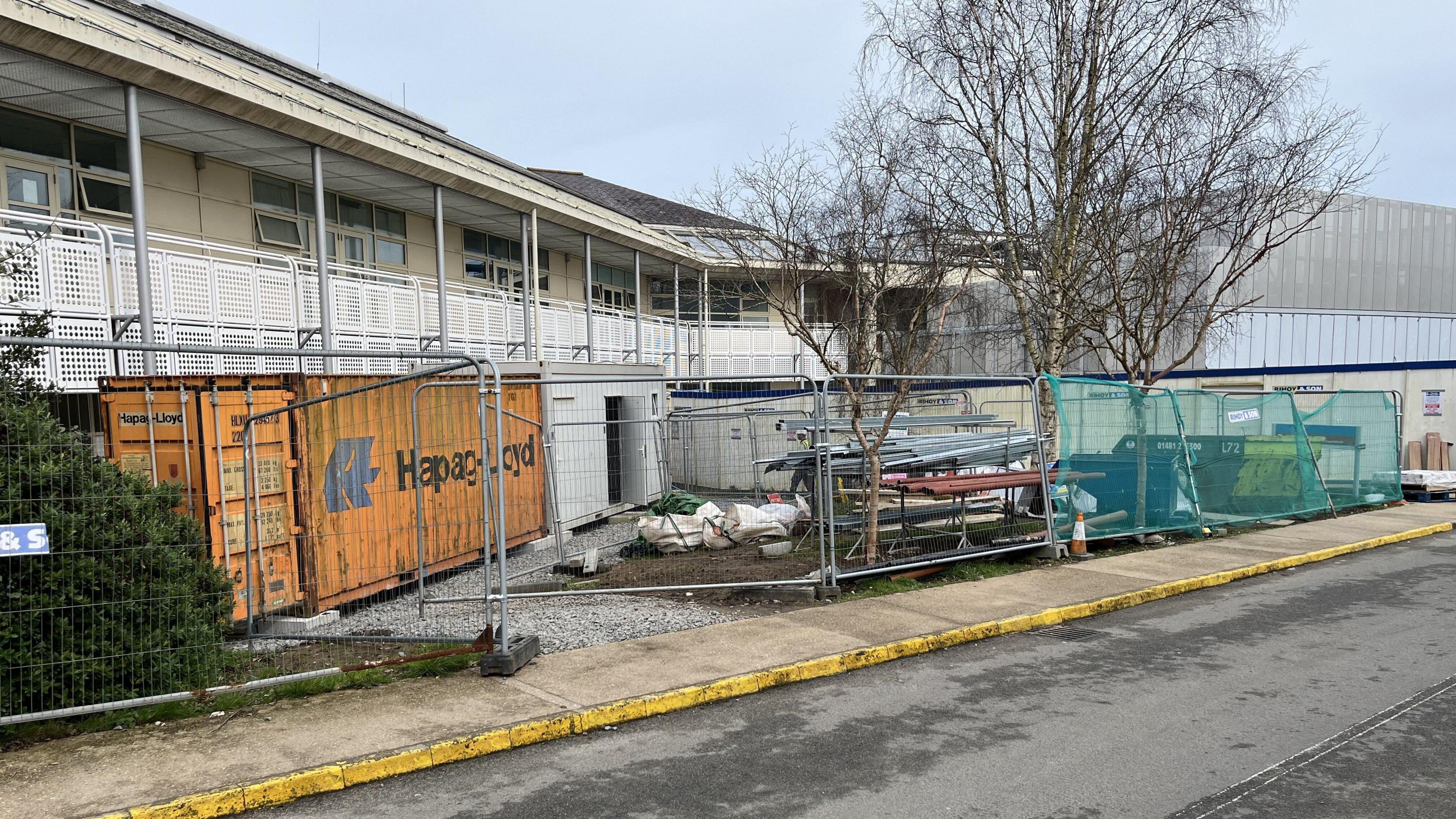 Building site outside Guernsey' Princess Elizabeth Hospital, with temporary fencing a yellow shipping container and other building equipment. 