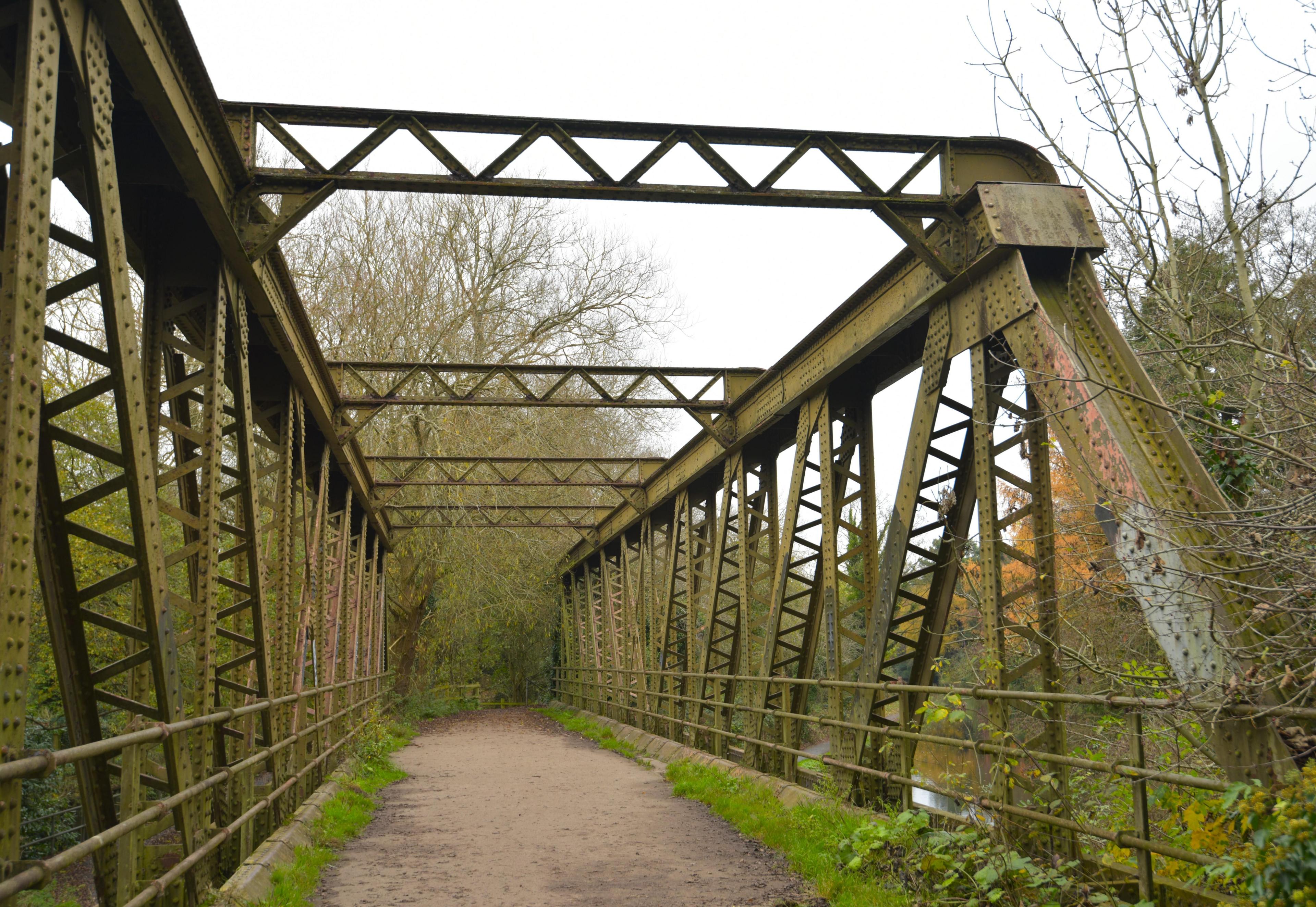 A bridge made of metal struts with prominent rivets, reminiscent of a Meccano model. The main structural lengths are solid metal, while other supports have zig-zag struts.  