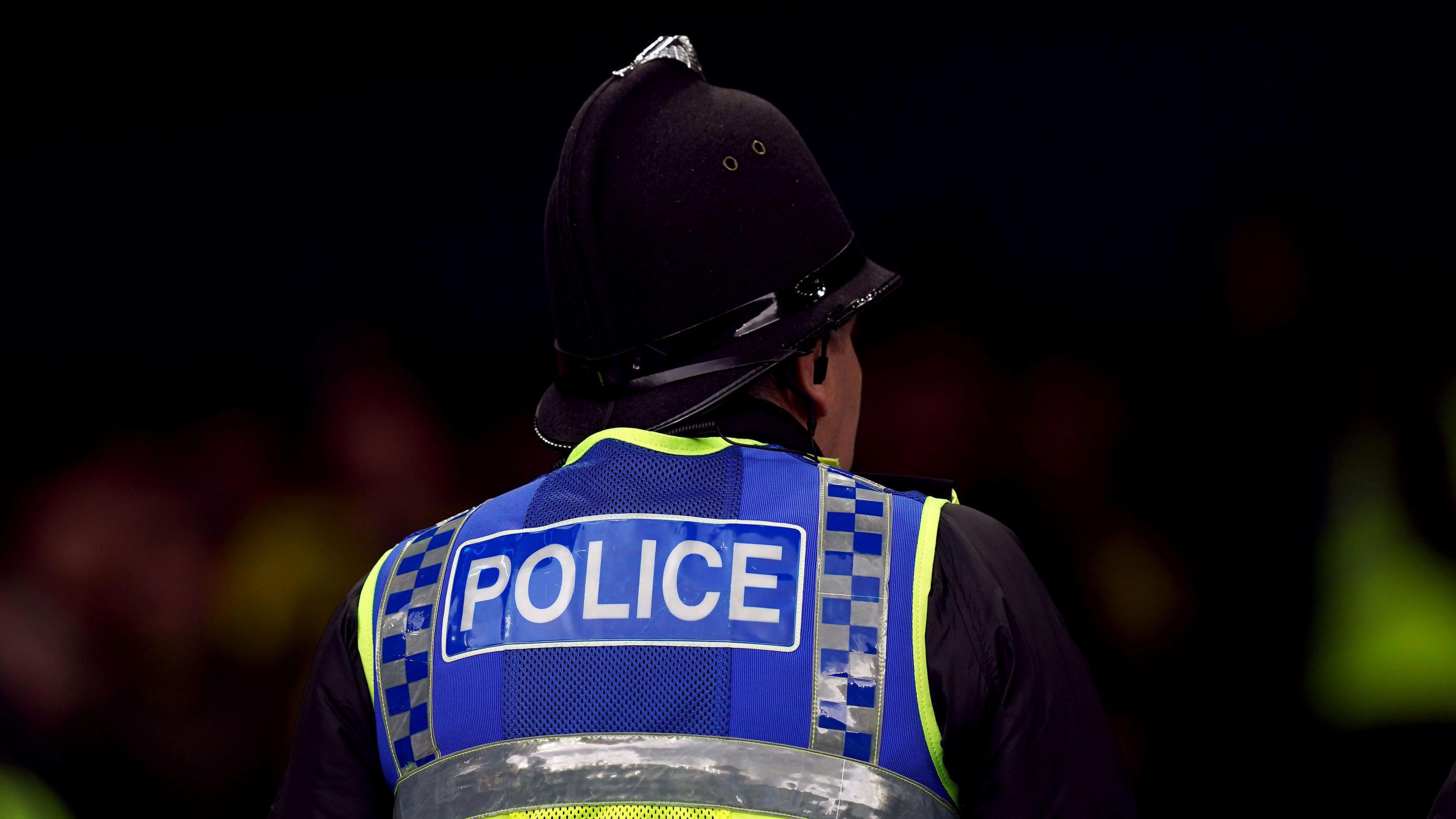 Close-up of the back of a police officer wearing a hi-viz vest