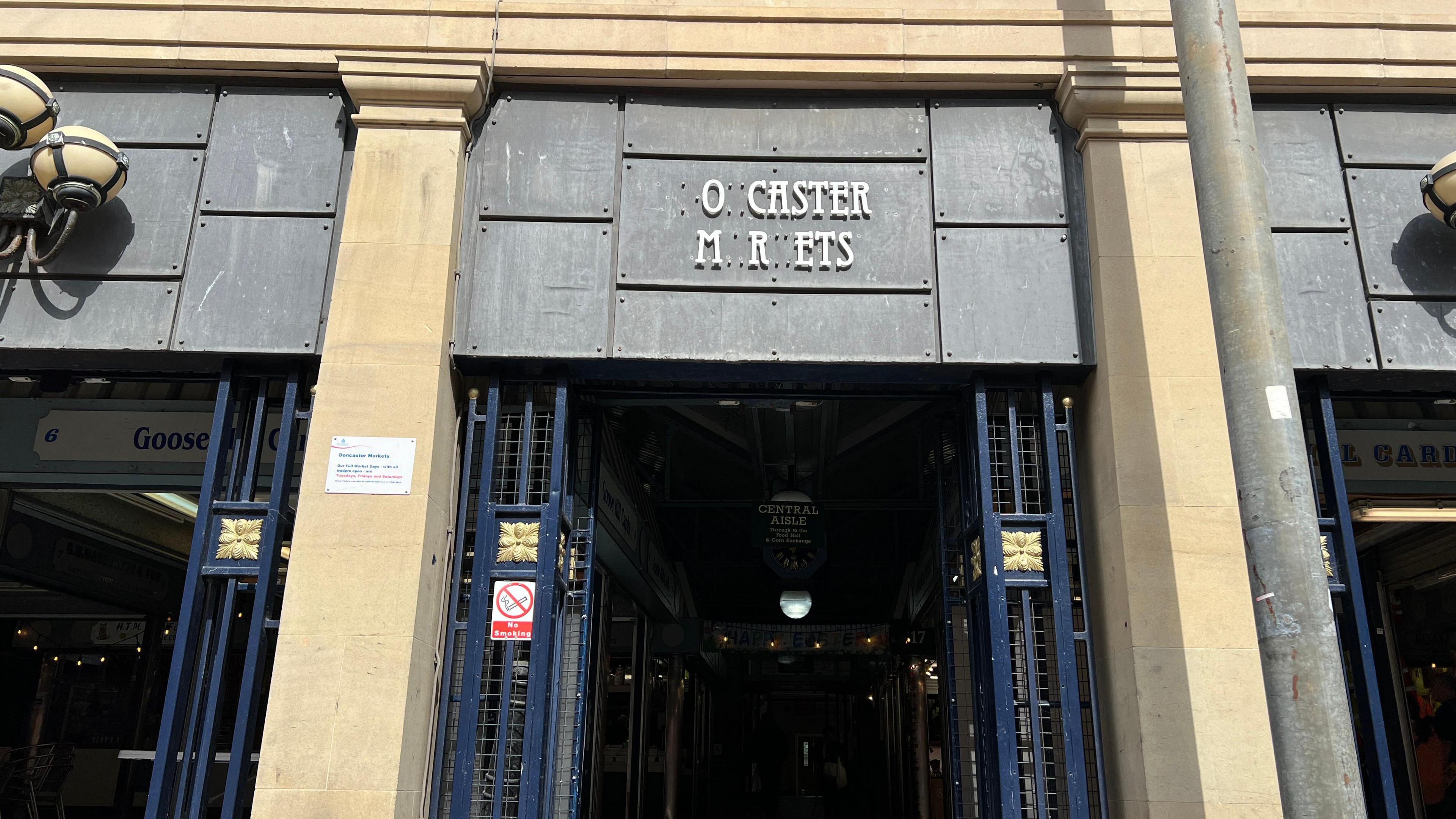 The entrance to a market. The sign, should read Doncaster Markets, but with its missing lettering it reads 'Ocaster Mrets'