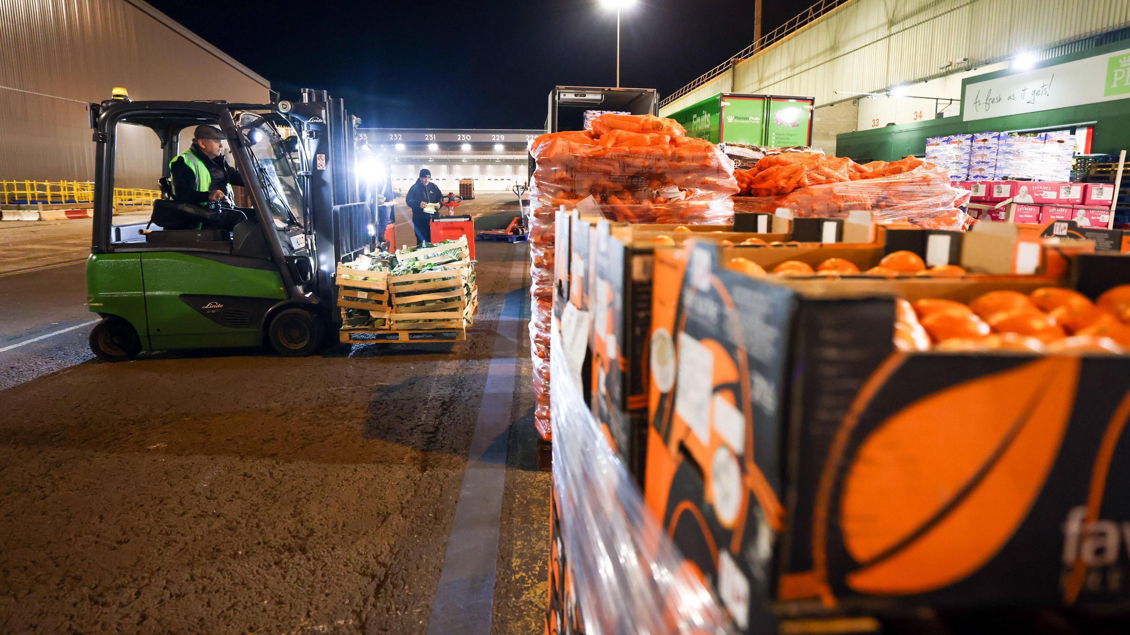 A forklift truck moves fresh vegetables at New Covent Garden Market wholesale market in London, U.K., on Wednesday, Sept. 29, 2021. In the foreground there are stacked boxes of satsumas or oranges.