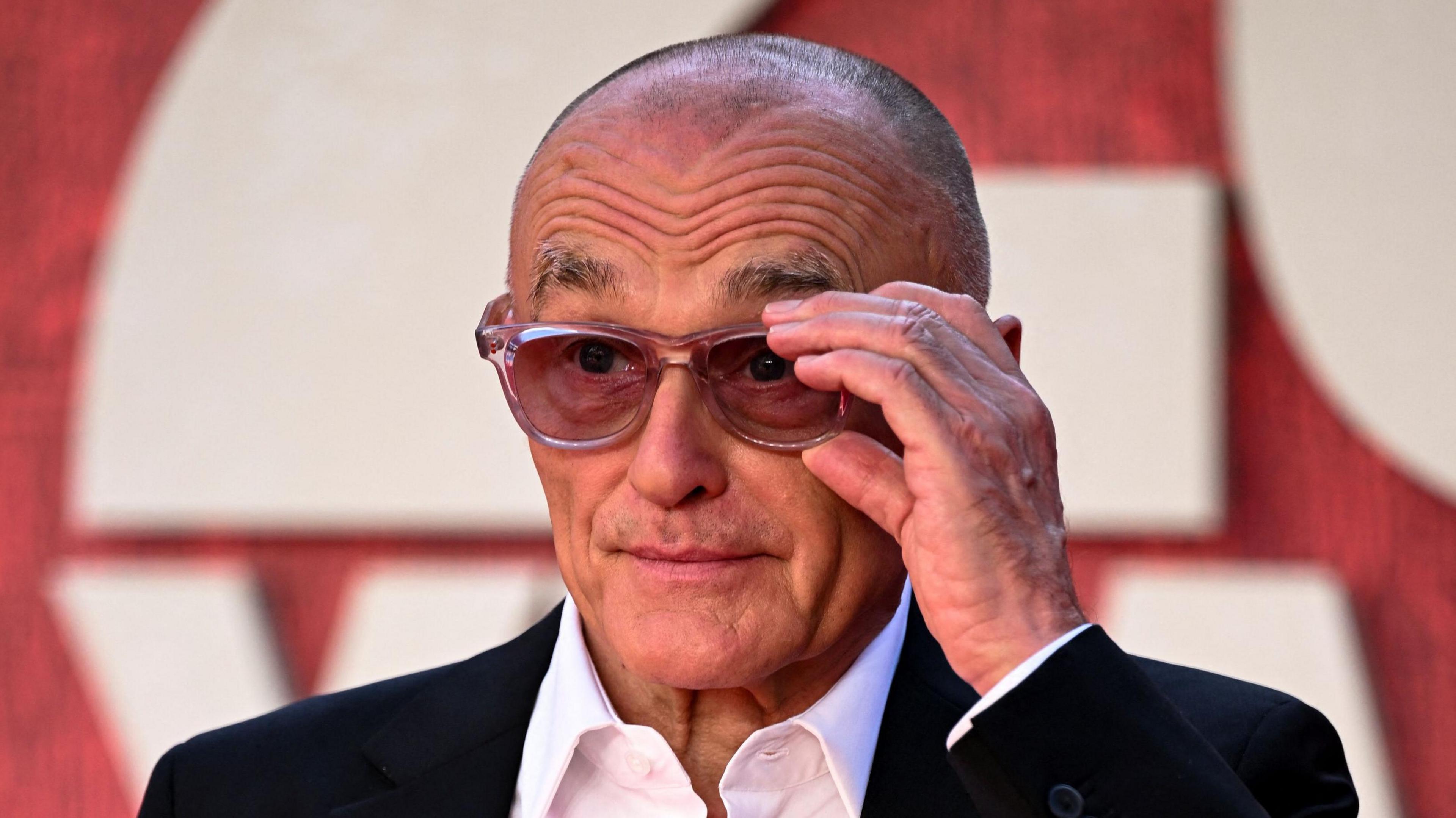 Danny Boyle adjusts his glasses as he poses for photographers at the 28 Years Later premiere.