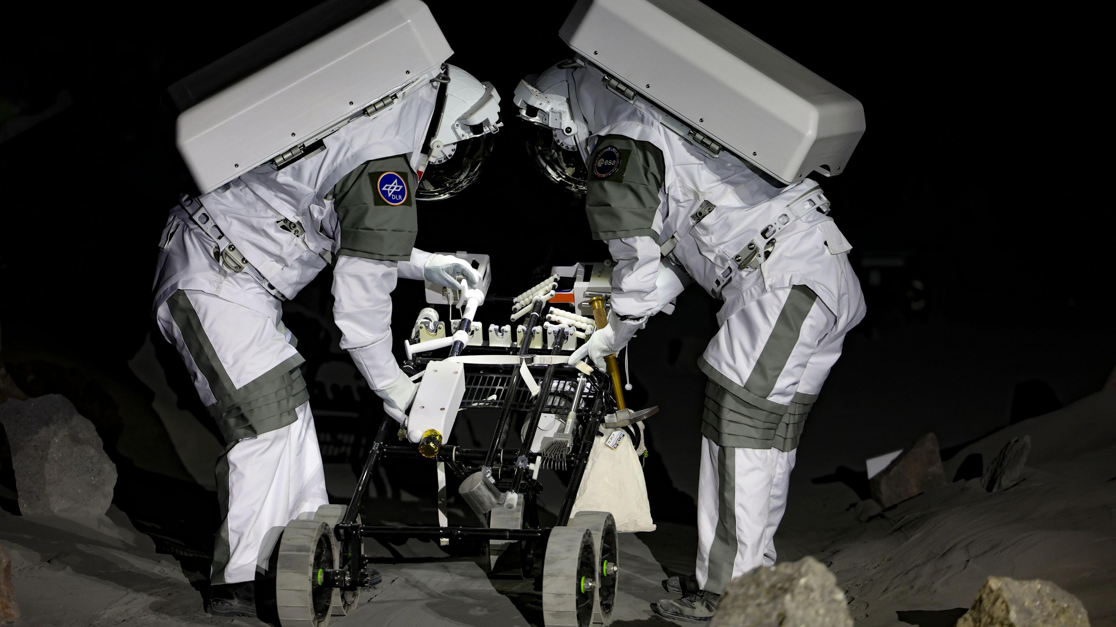 Two astronauts working on the replica of the surface of the moon