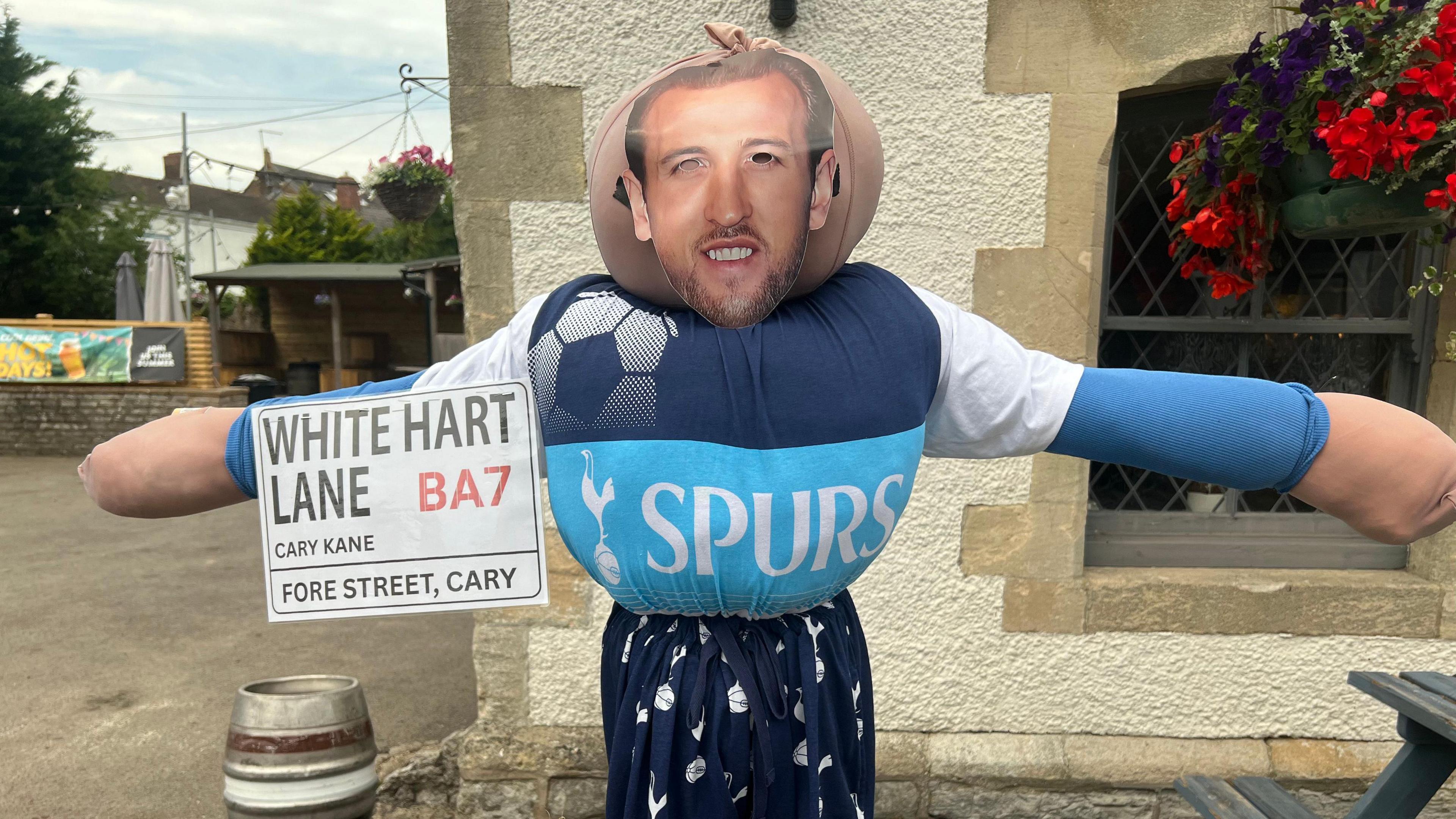 A Harry Kane mask stuck on a scarecrow in a market town