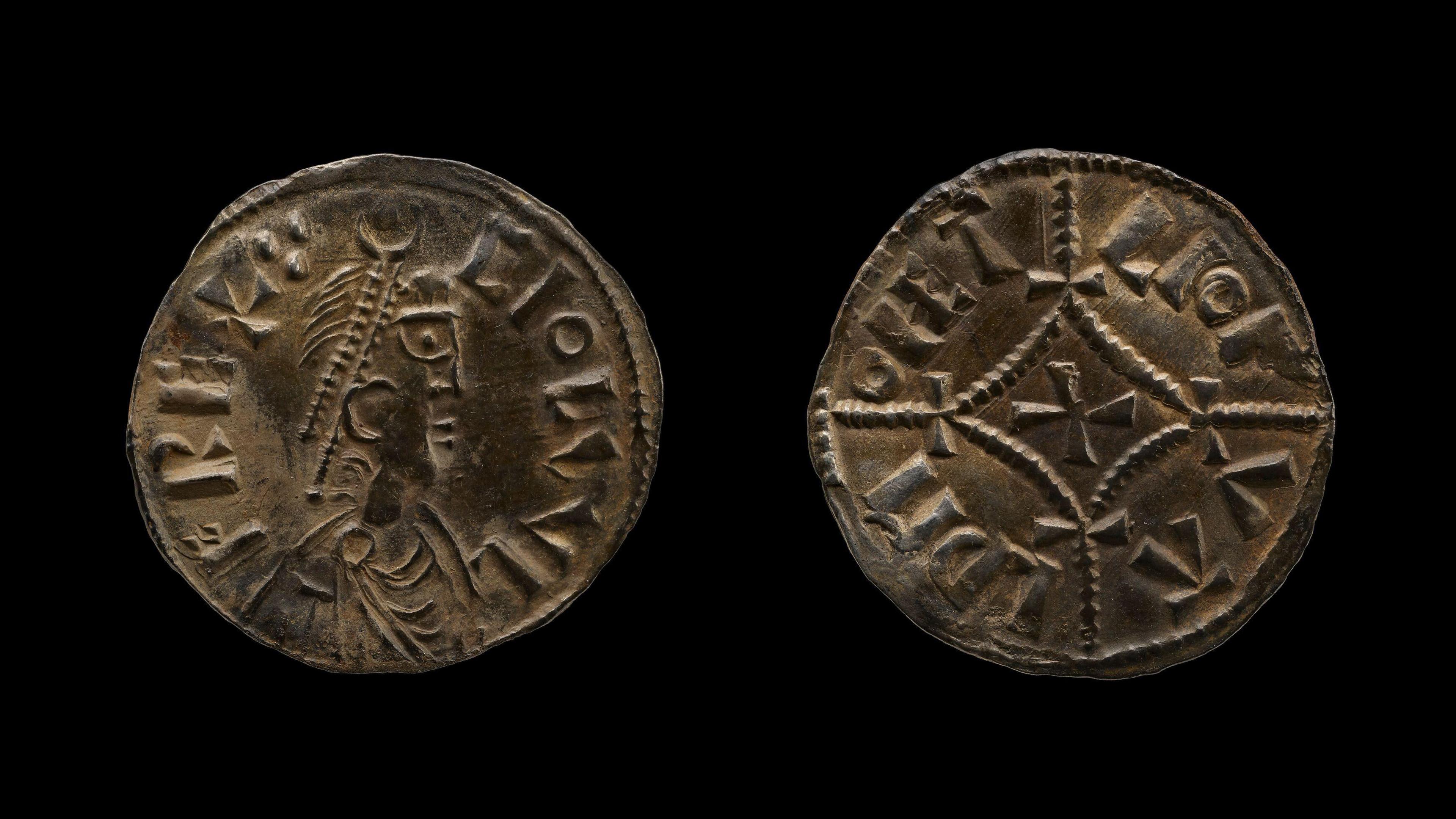 Undated handout photo issued by the British Museum of two ancient metal coins with an emperor on one coin and a cross in the middle of the other. They are on a black background.