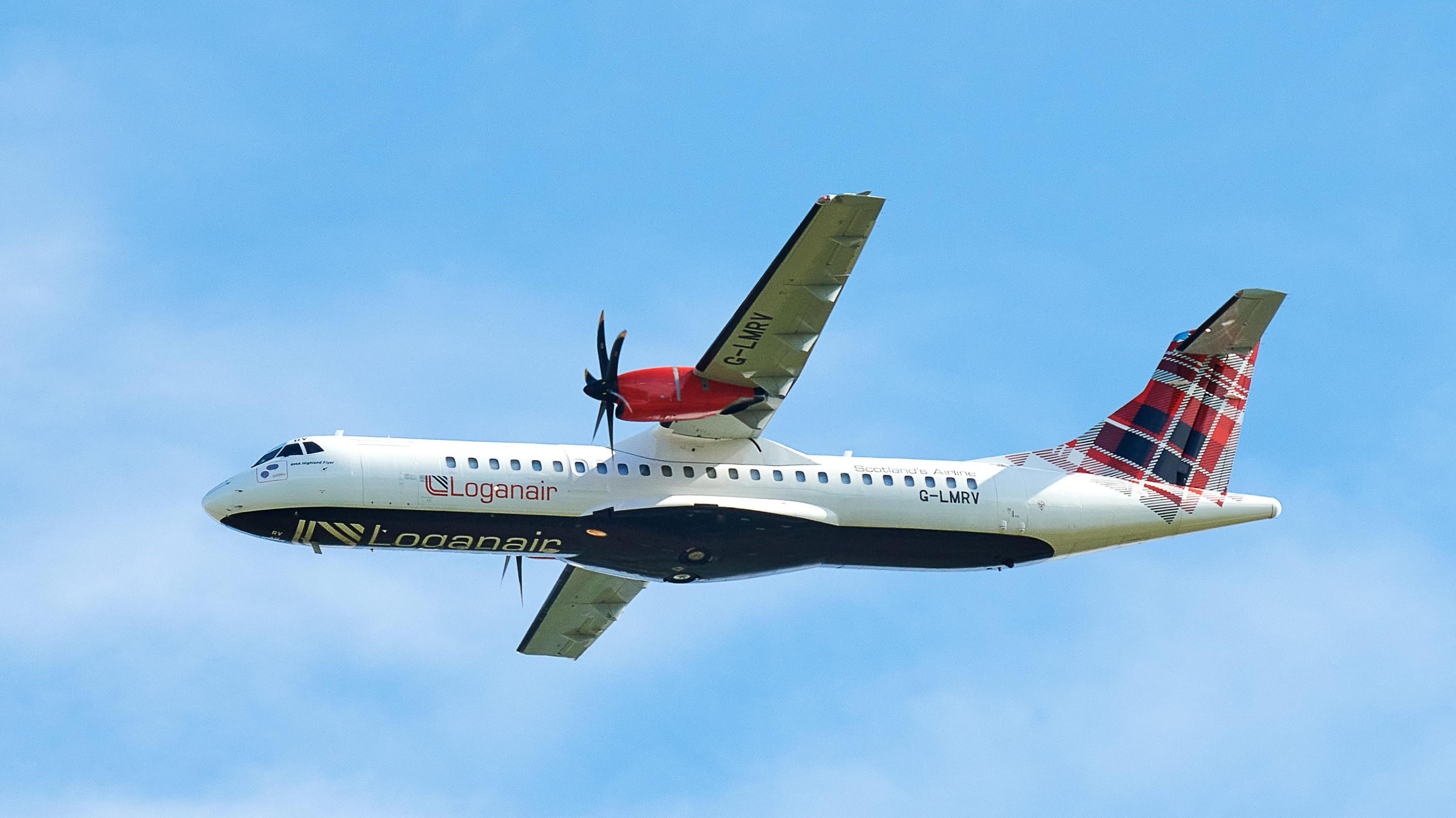 A Loganair aircraft with its distinctive livery is parked on the tarmac at an airport, with a backdrop of a runway and terminal buildings.