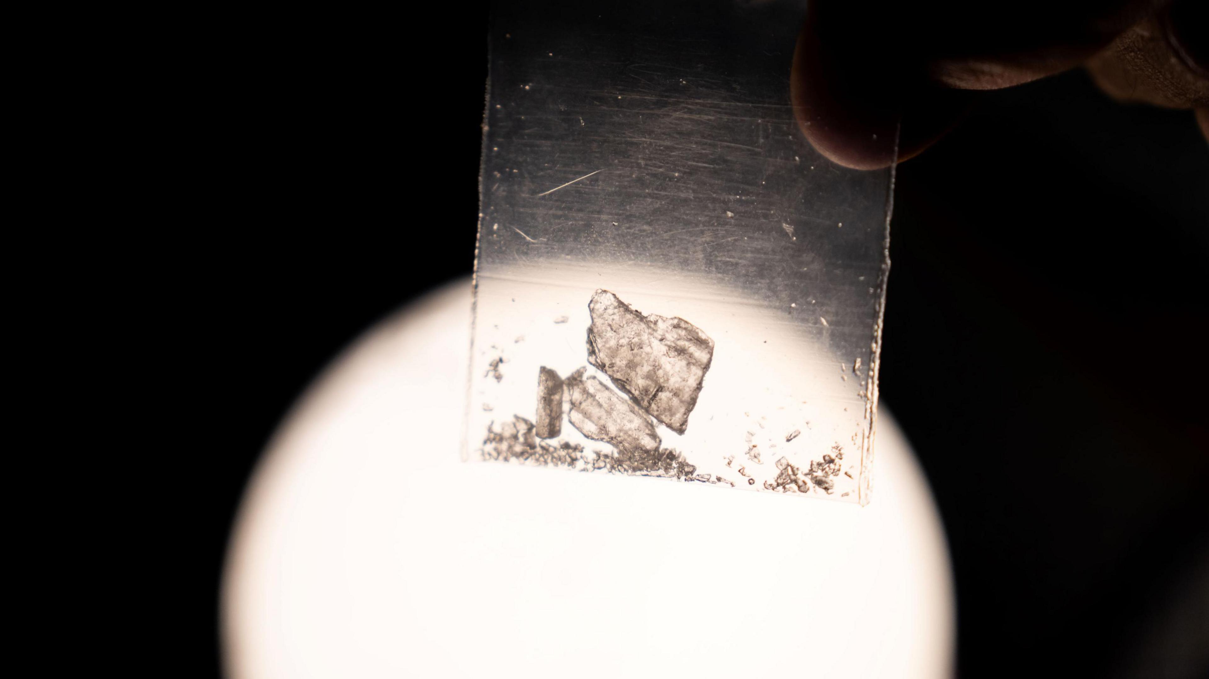 A crystallised substance in a small plastic bag in front of a bright light