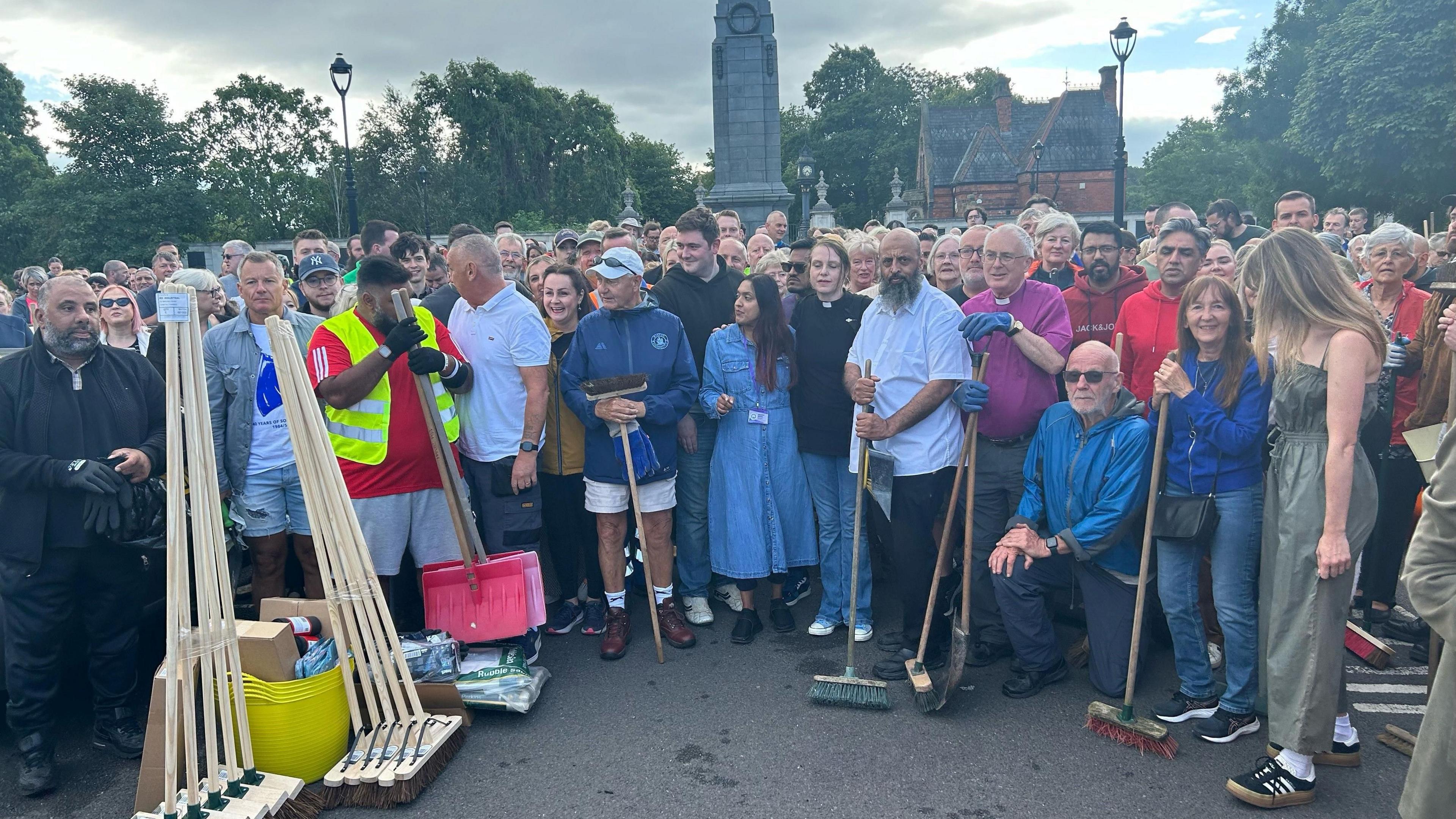 A crowd of clean-up volunteers holding brushes at Middlesbrough's cenotaph.