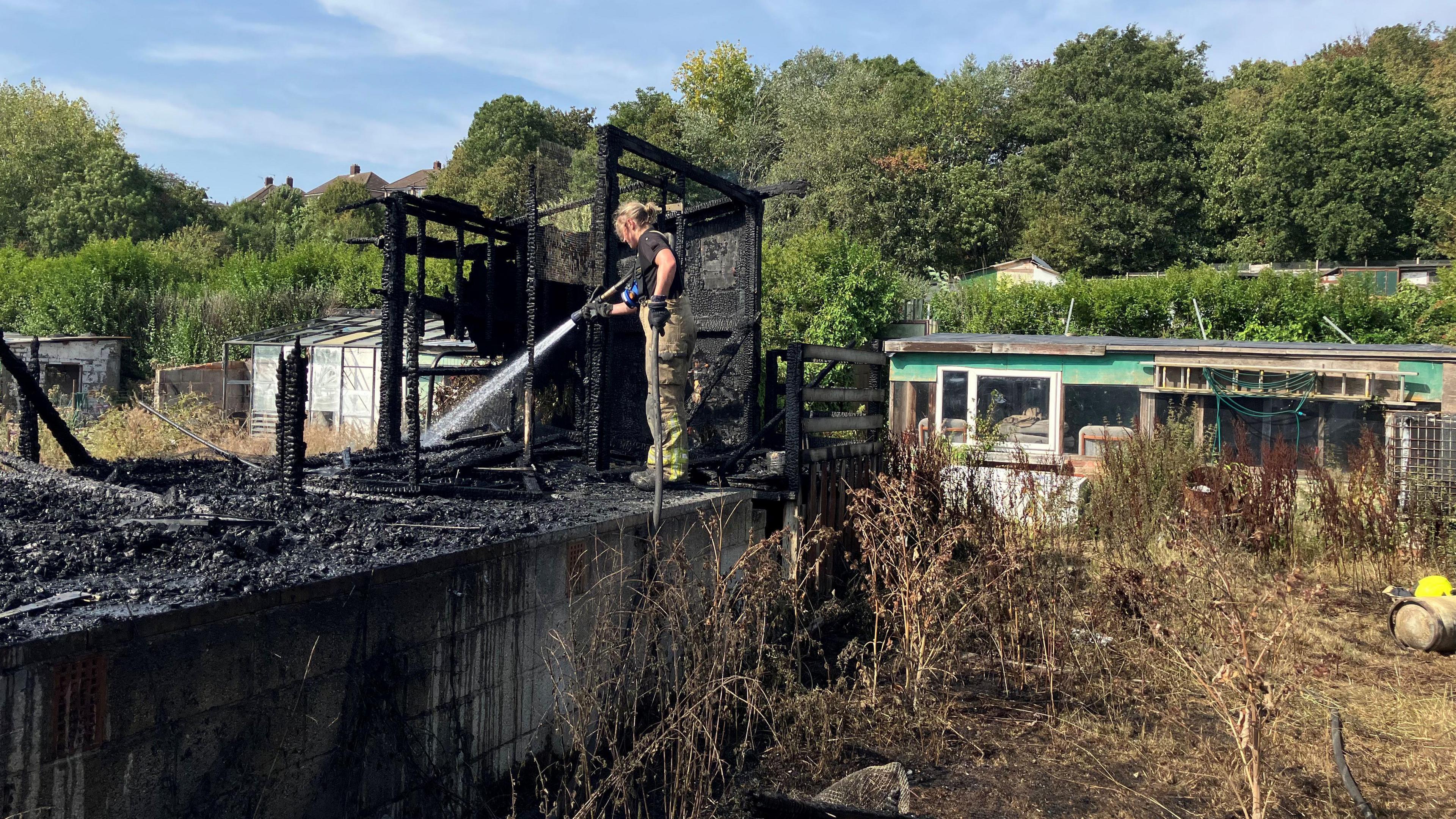 Firefighter hosing down burned building