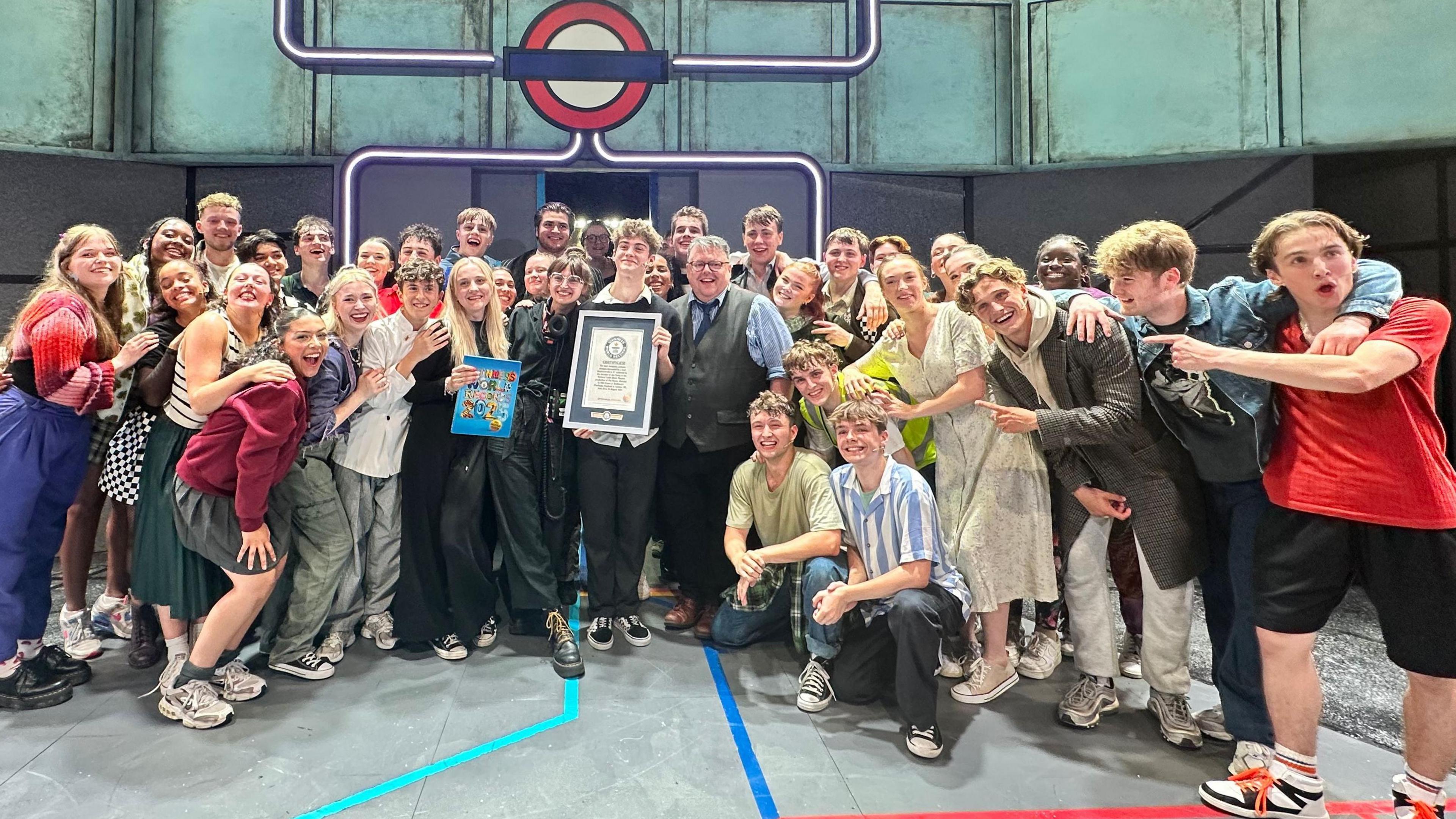 Cast and crew of the National Youth Music Theatre on stage celebrating their win 