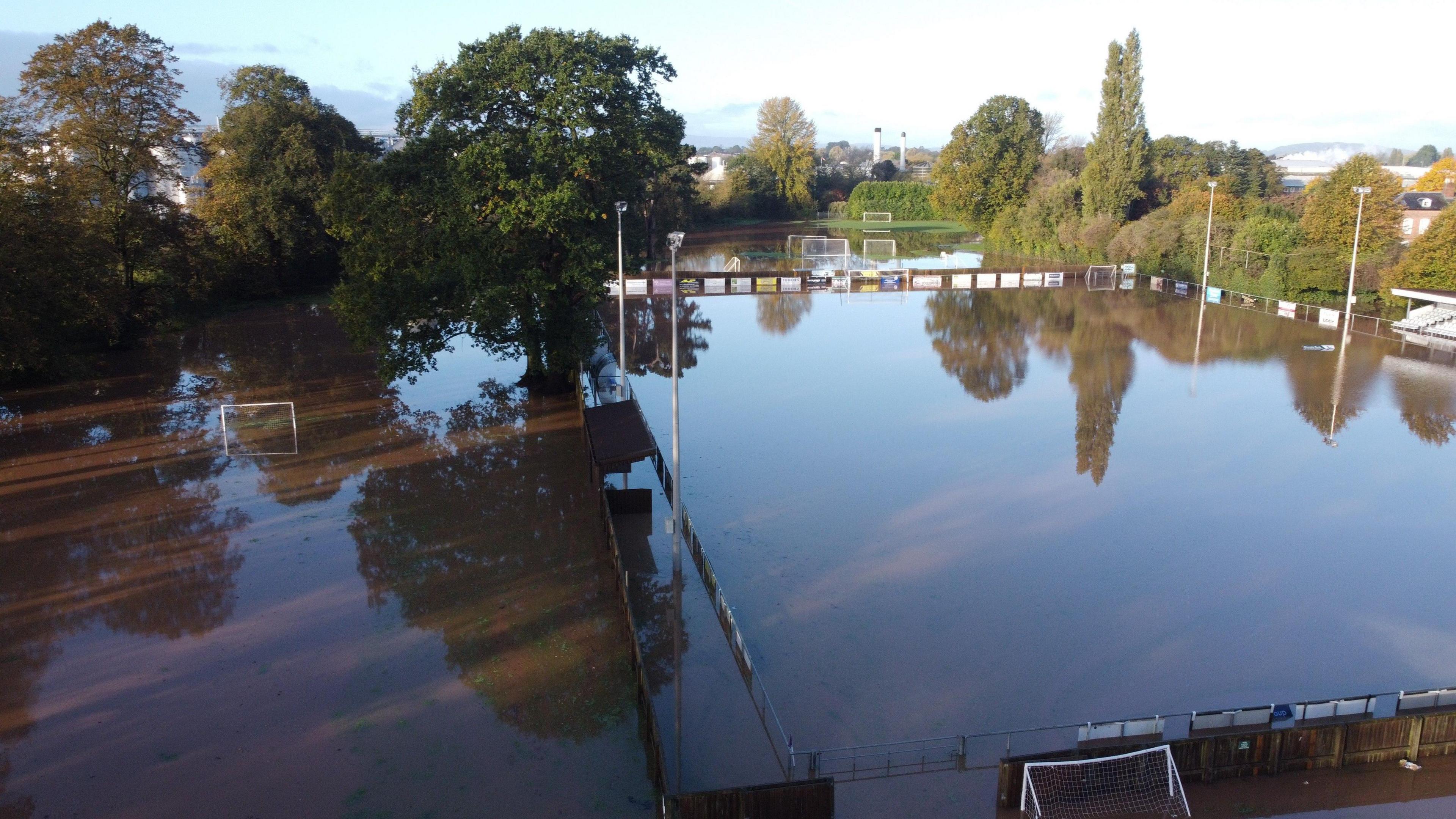 A football pitch flooded with brown flood water