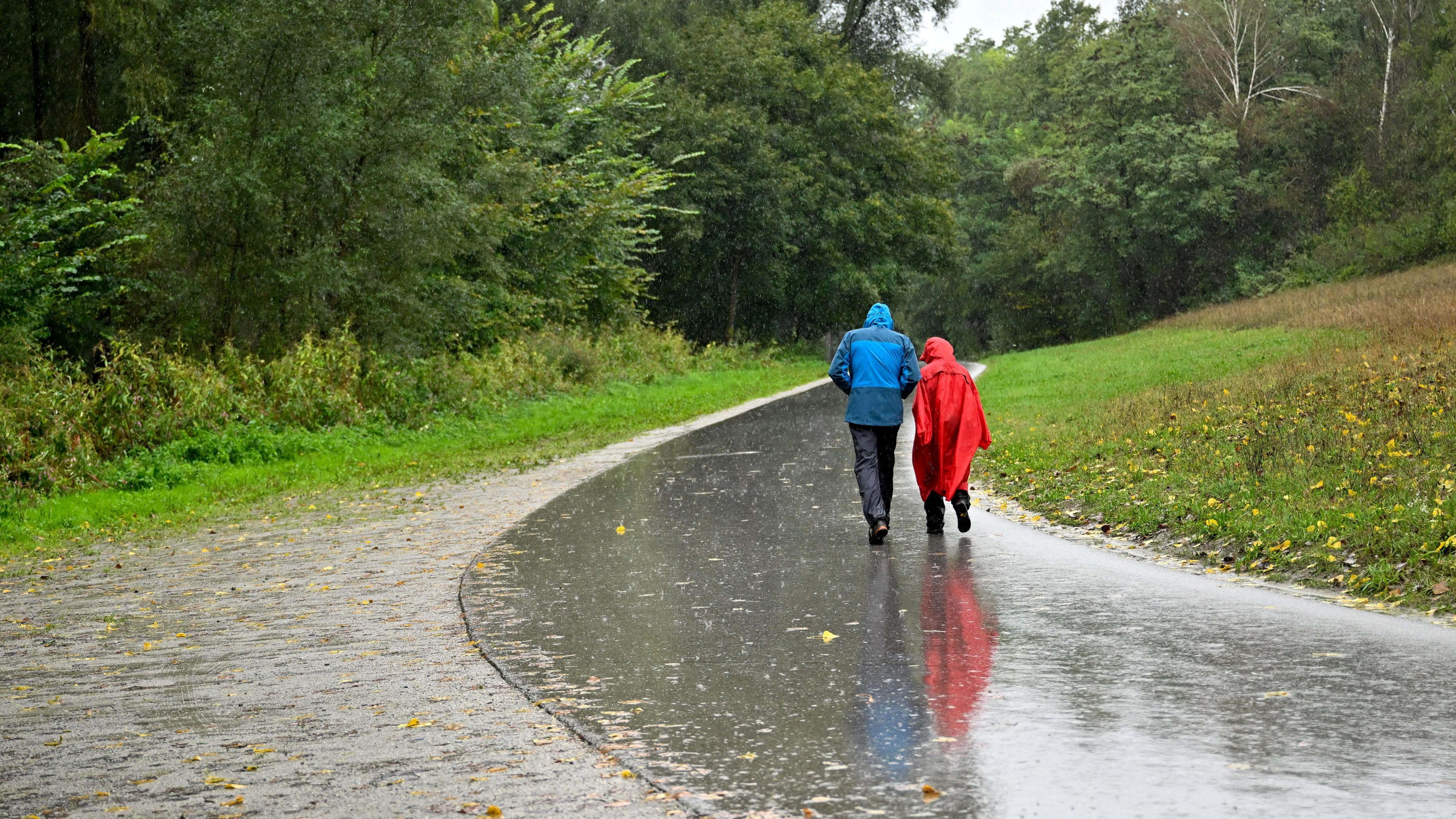 People walk in heavy rain in Ottensheim after Austrian forecasters expanded a warning for extreme rainfall to areas of the country.