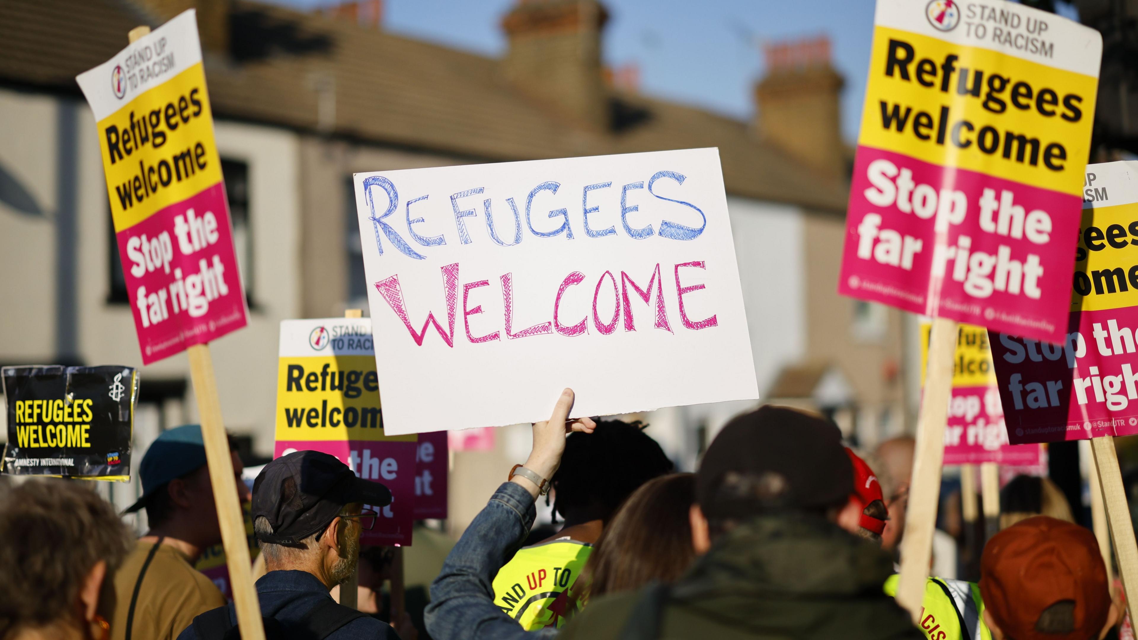 "Refugees welcome" banners and the back of counter protesters heads