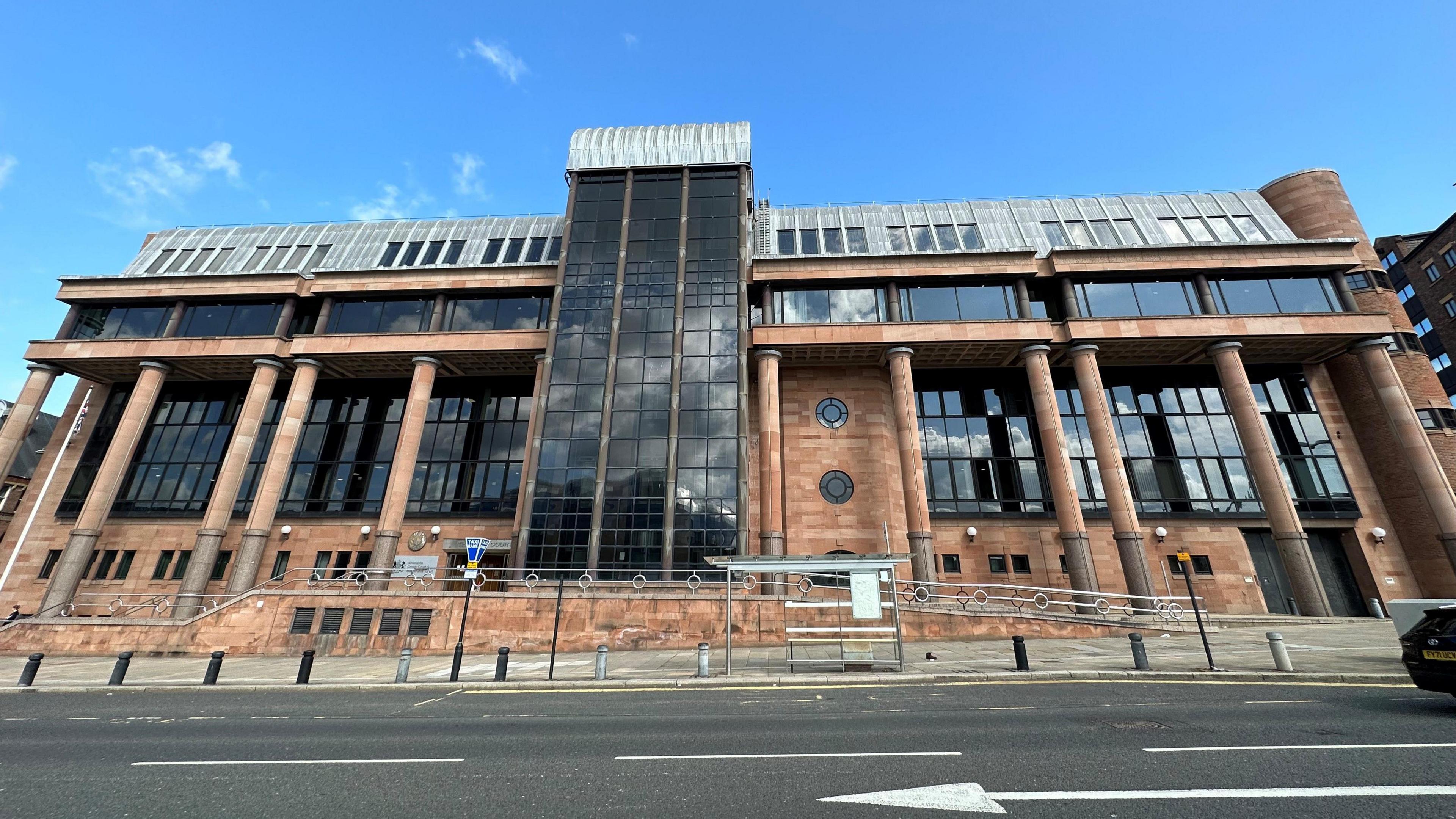 Newcastle Crown Court building. It is made from red bricks and columns with large dark windows.