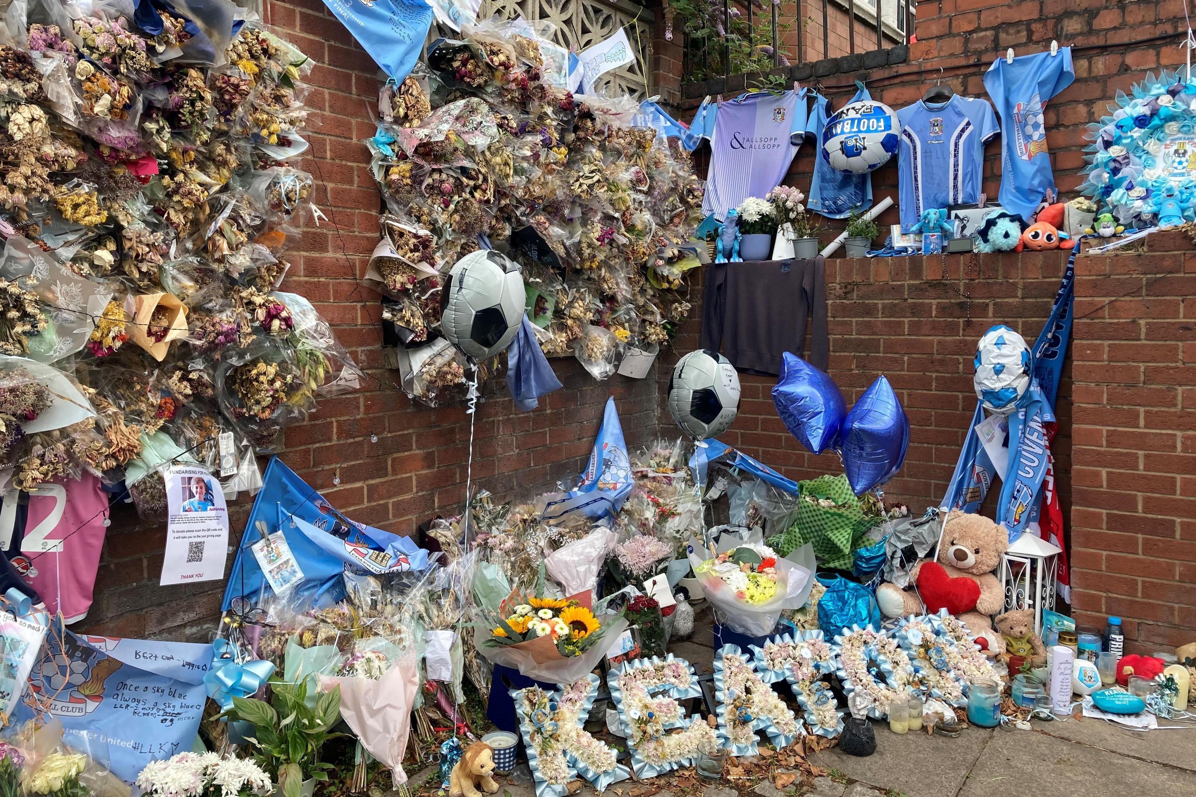 Lots of tribute flowers and a floral sign that says Keaton