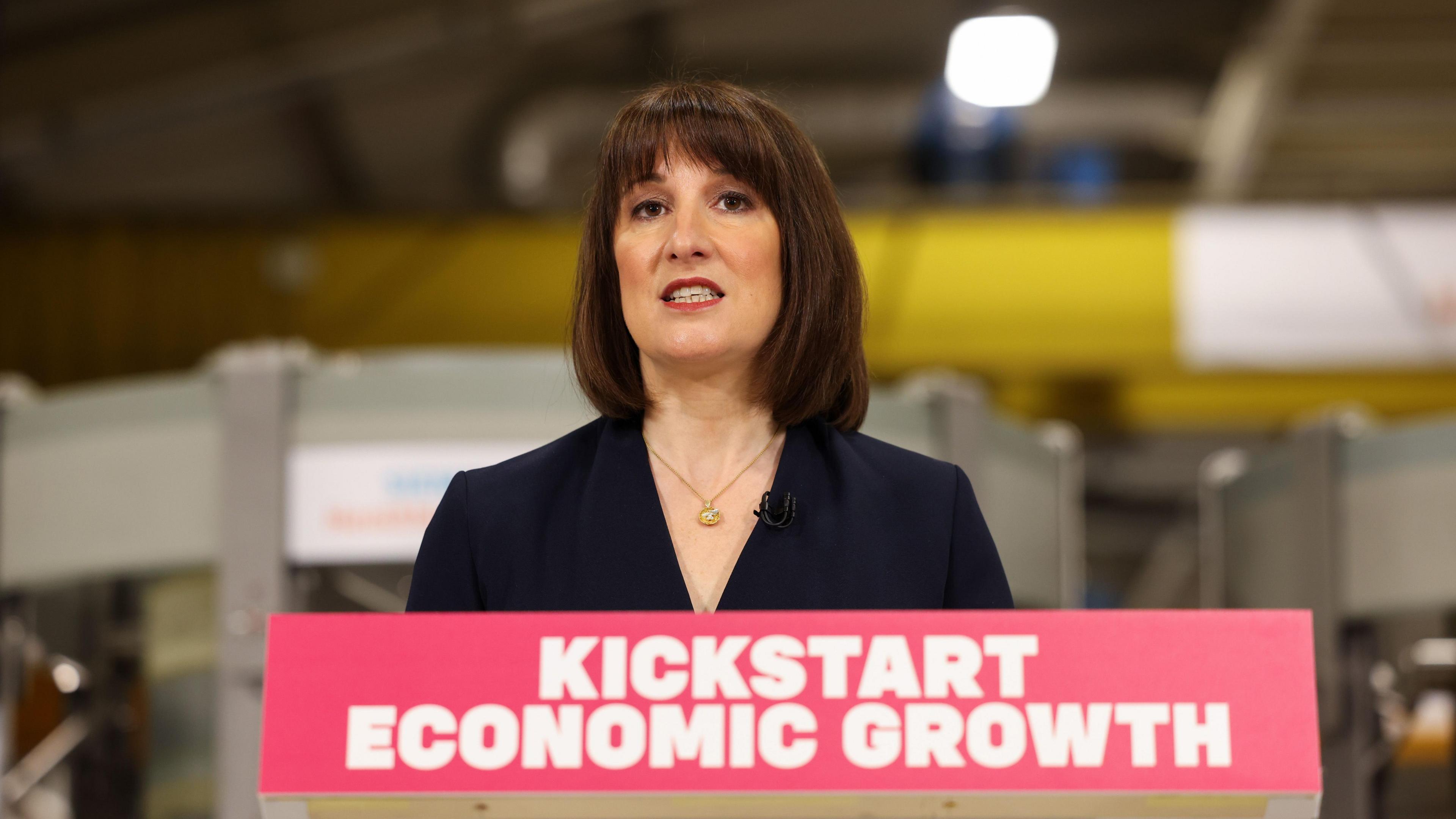 Chancellor Rachel Reeves stood at a podium which reads KICKSTART ECONOMIC GROWTH