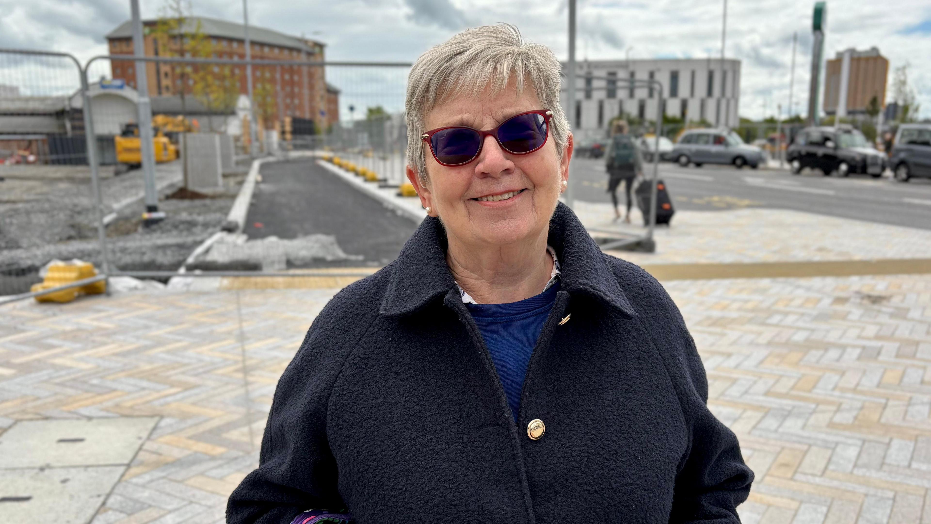 Dorothy Turnbull. She has short grey hair, wearing sunglasses, a black coat and blue jumper.
