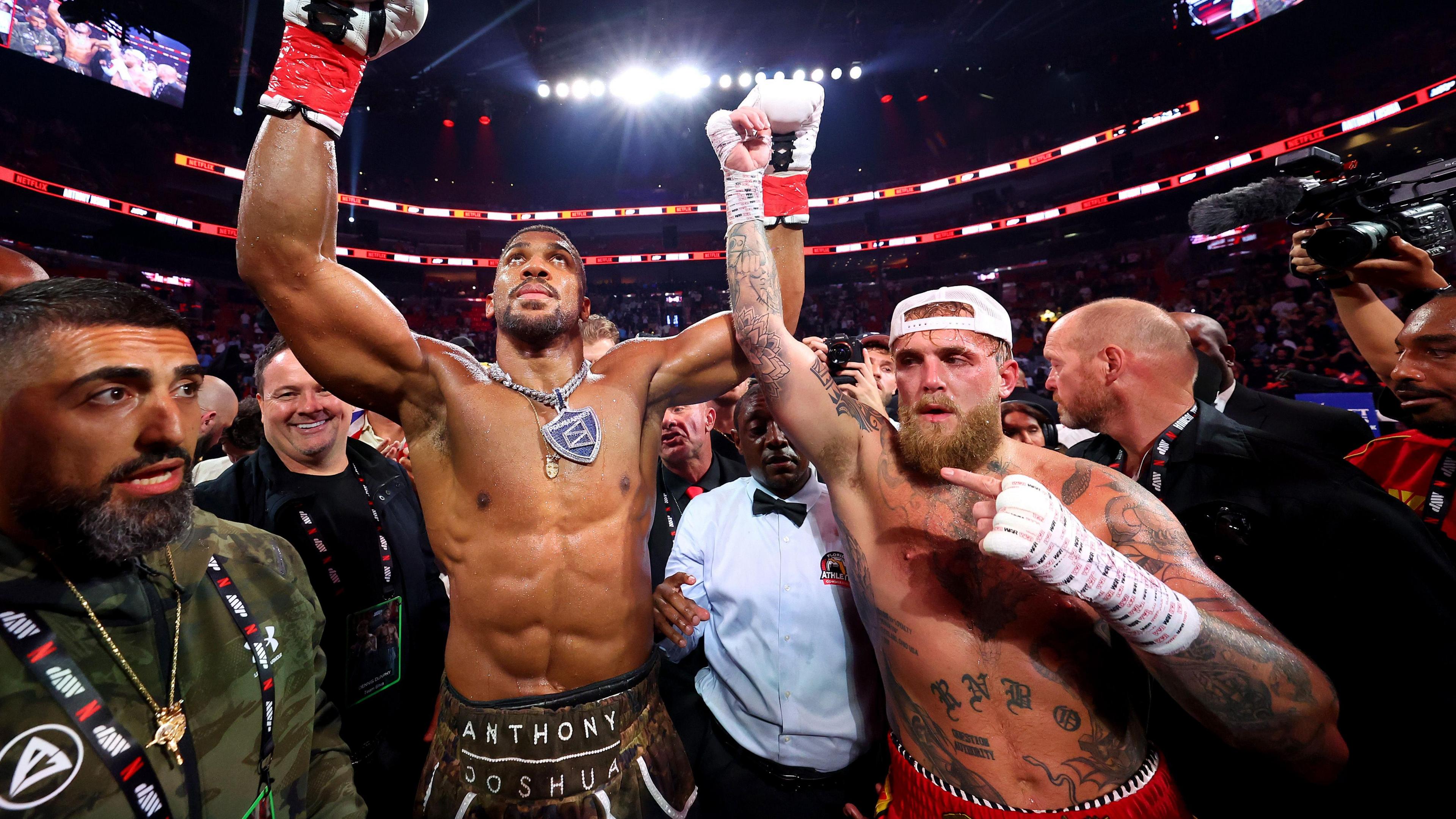 Sina Ghami pictured in a busy boxing ring with boxers Anthony Joshua and Jake Paul at the end of their recent fight