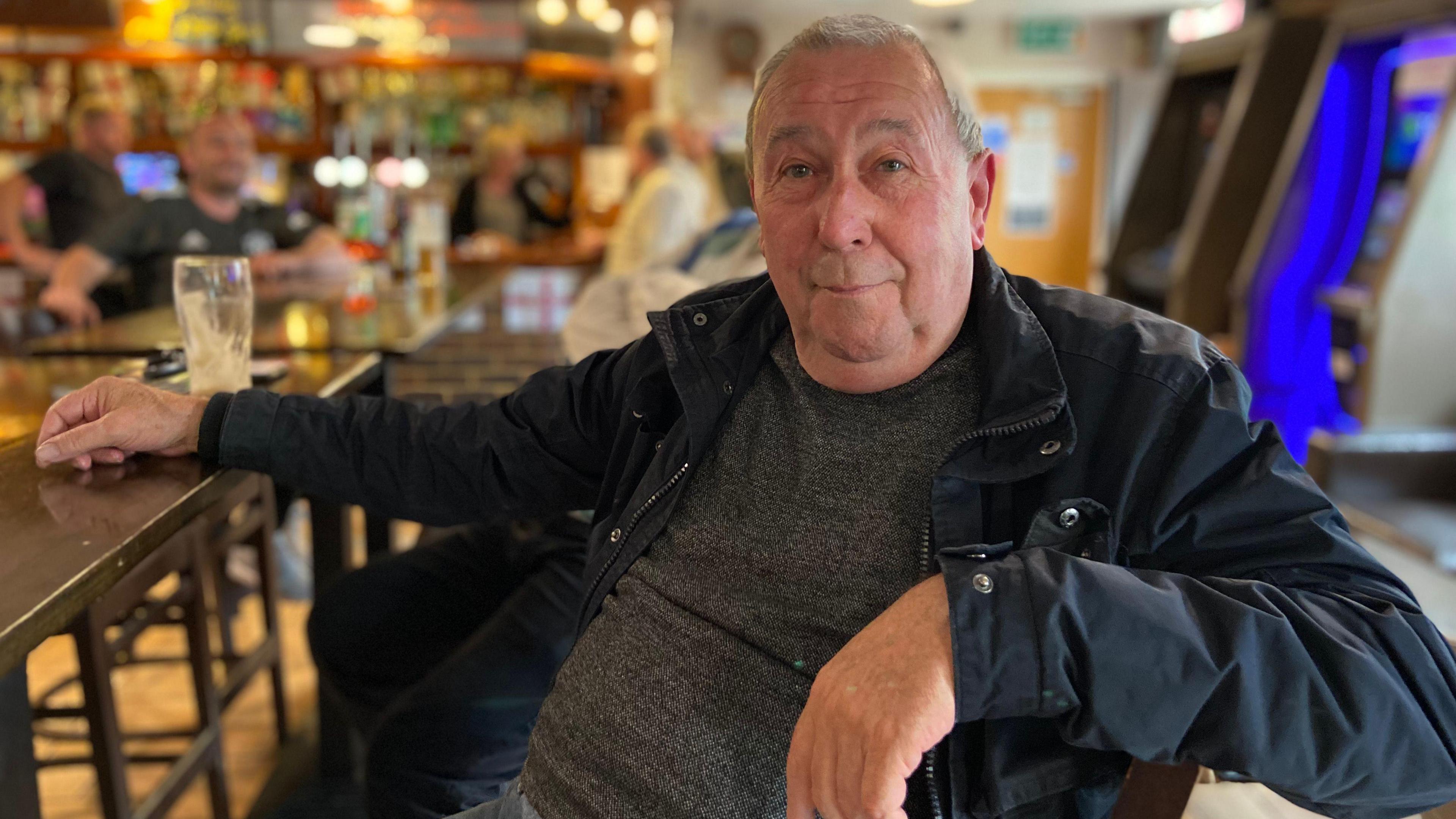 Stuart Noakes sits at a table in a social club