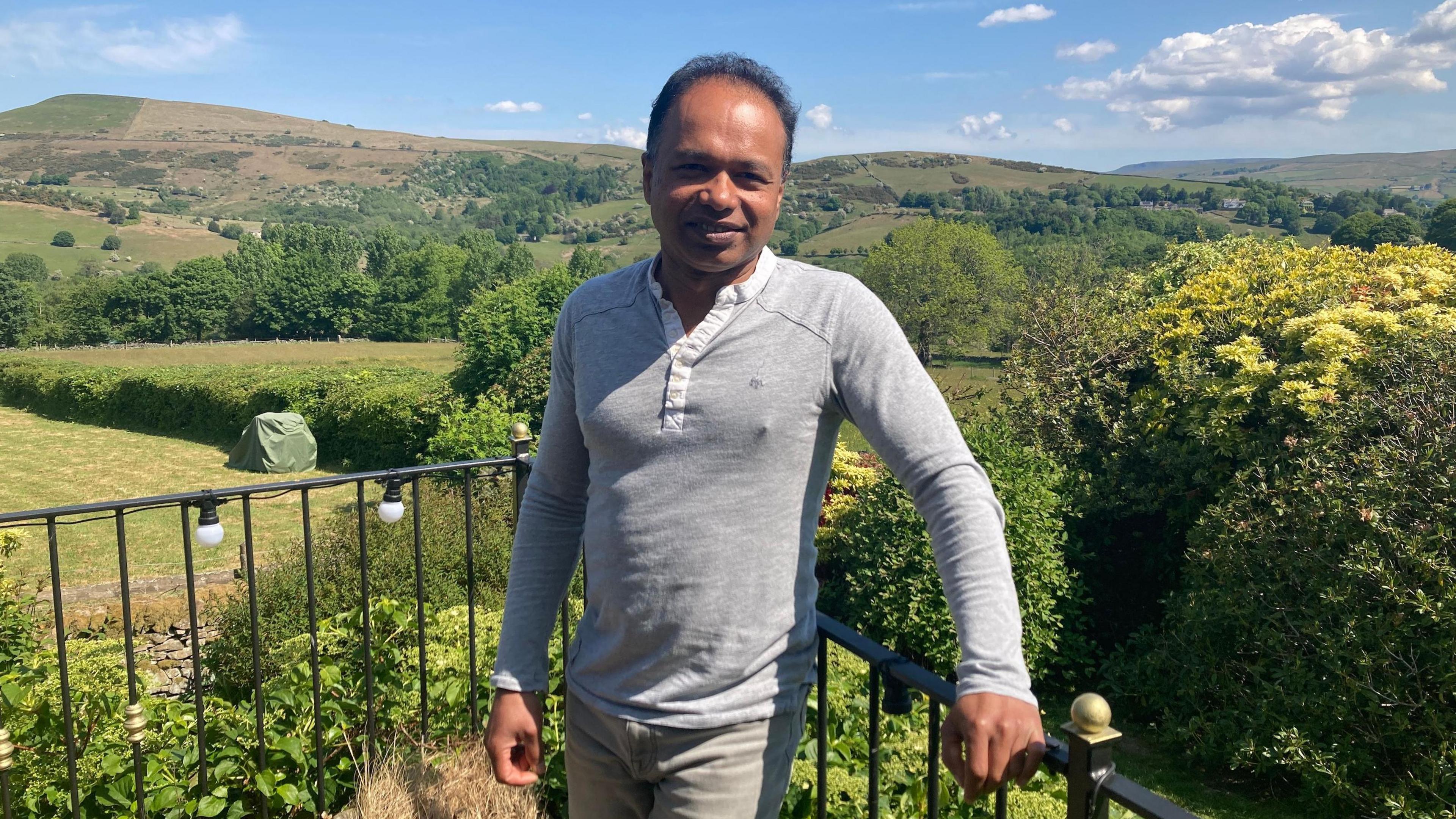 Neelanga Uggalle standing in his garden with a view of the surrounding countryside.