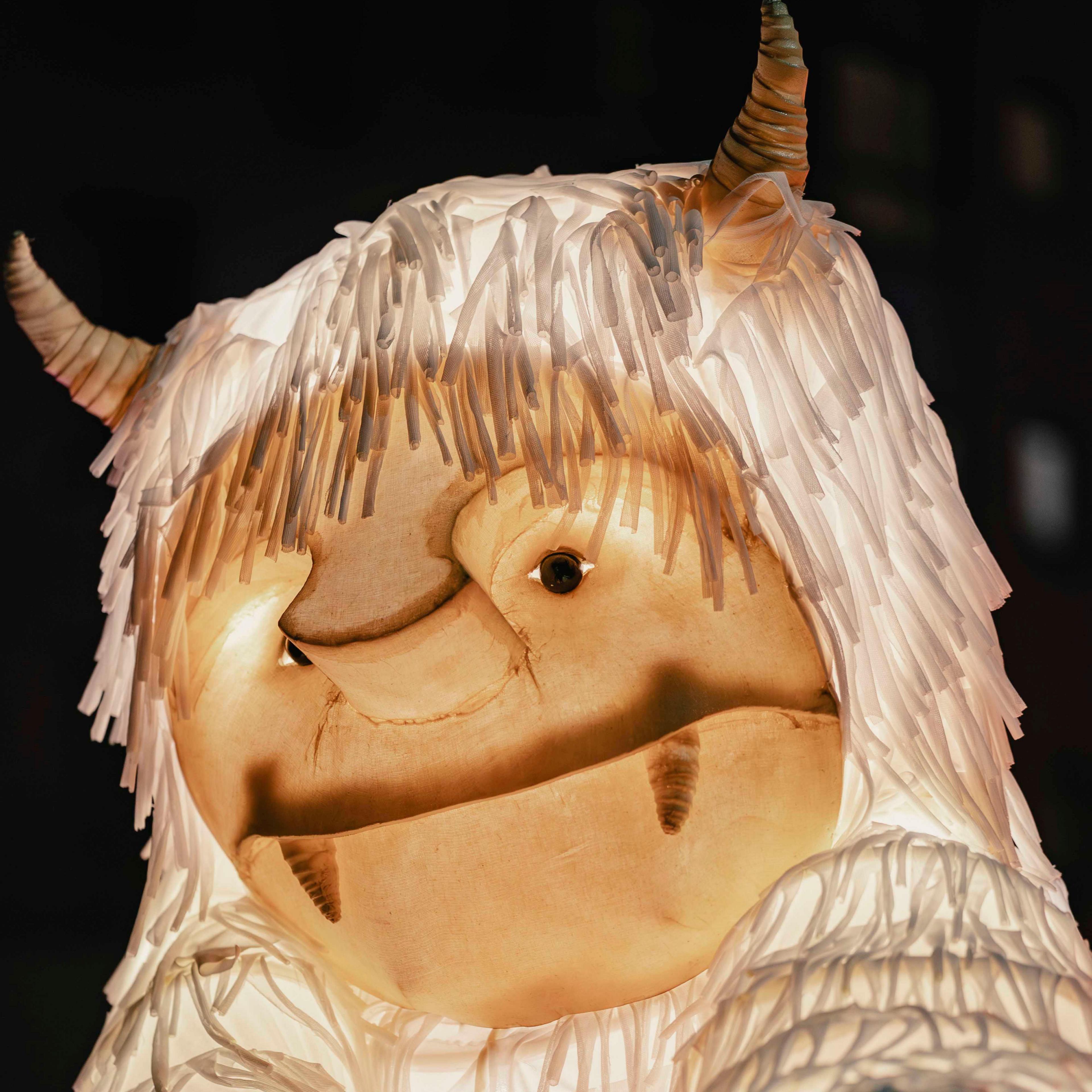 A parade costume depicting a large white hairy horned creature, with tusks and beady eyes.
