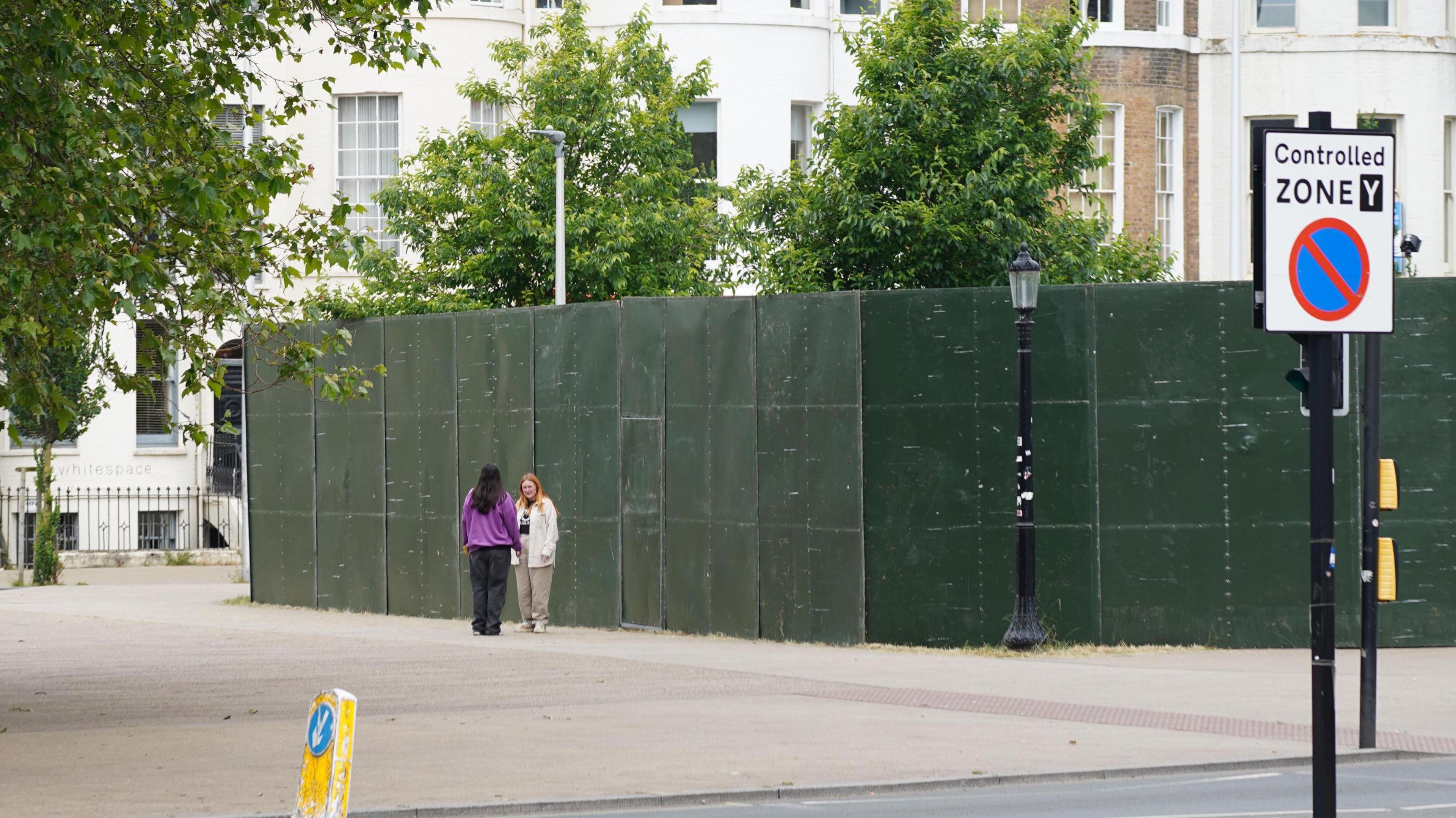 Two people stood next to 15-feet high green panels