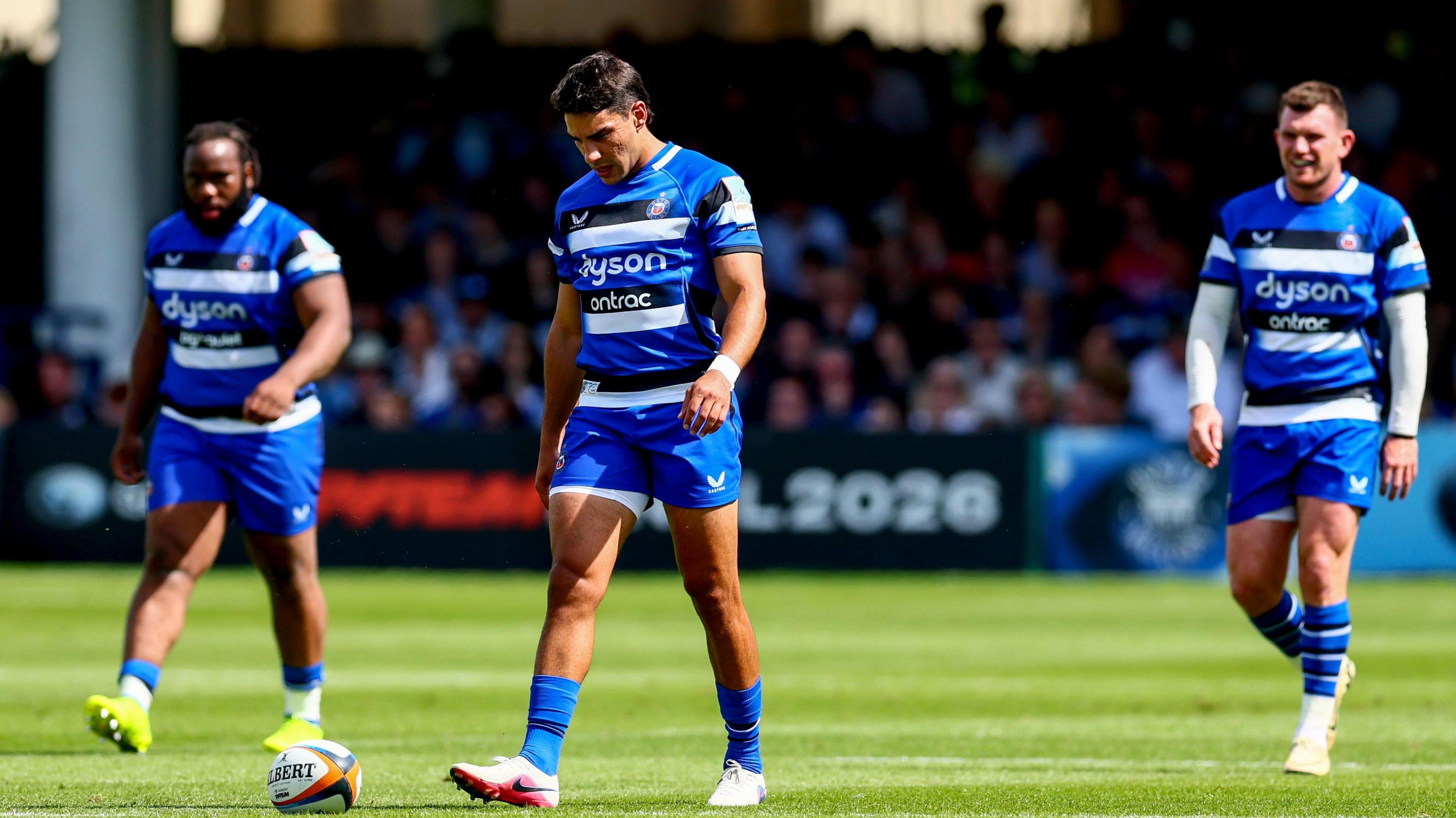 Beno Obano (left), Santiago Carreras (centre) and Ben Spencer (right) walk on the pitch looking dejected after the full-time whistle against Exeter