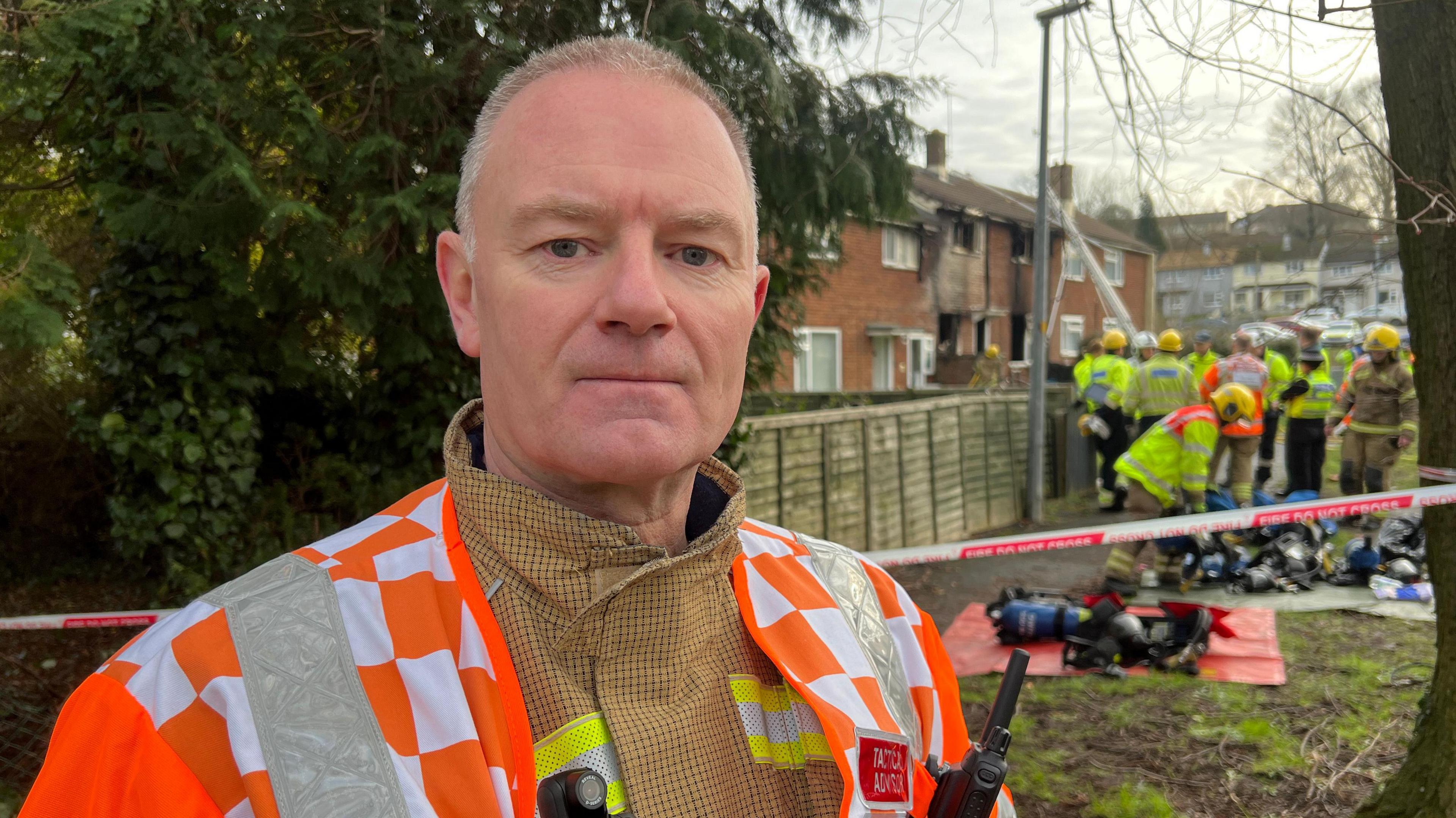 Wayne Jones, stood outside the burnt out house on Imber Walk. He is wearing a fire officer uniform.