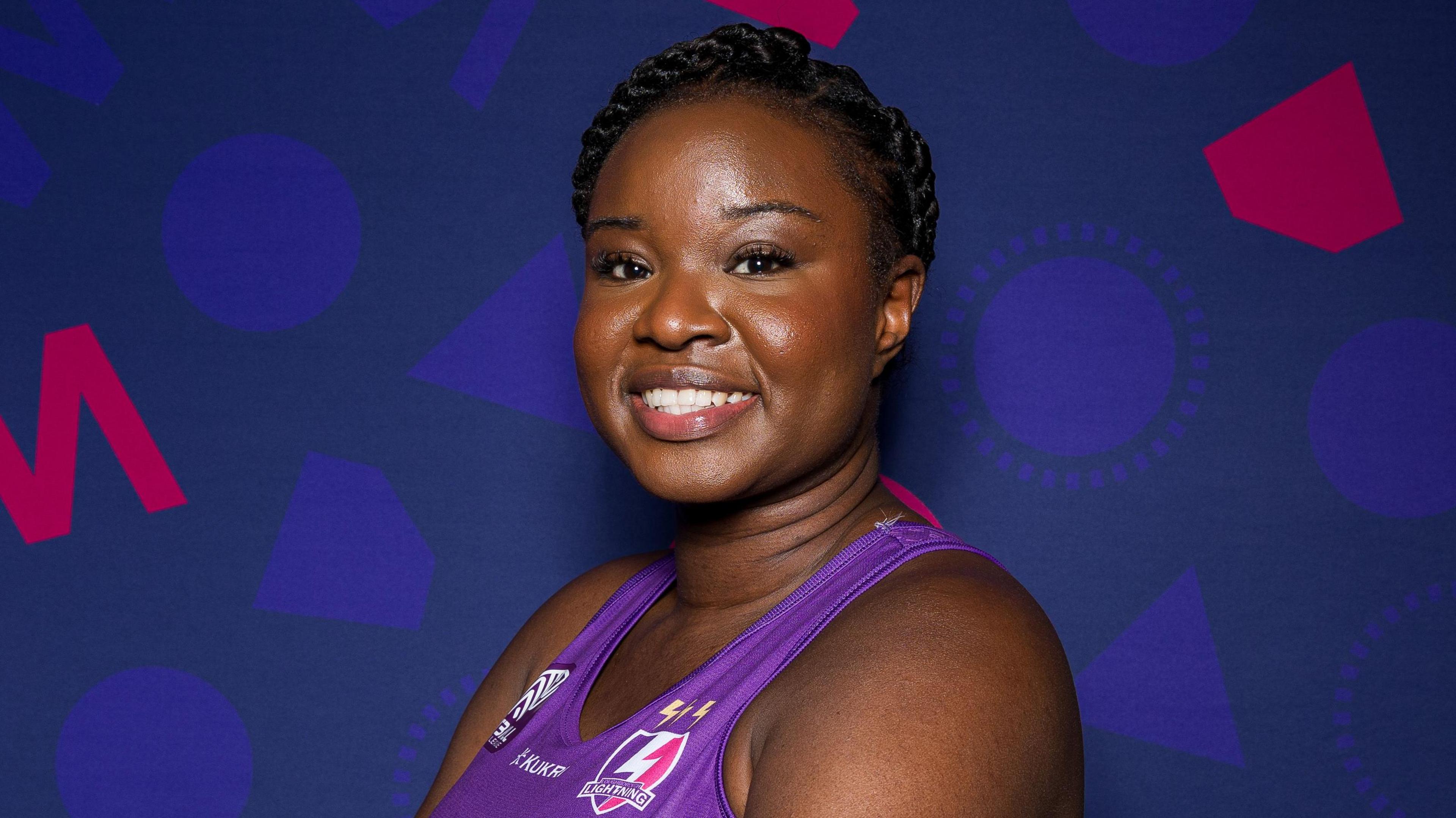 Dark-haired Sammy Wallace-Joseph smiling wearing a purple Loughborough Lightning vest. Her hair is tied back in a braid.