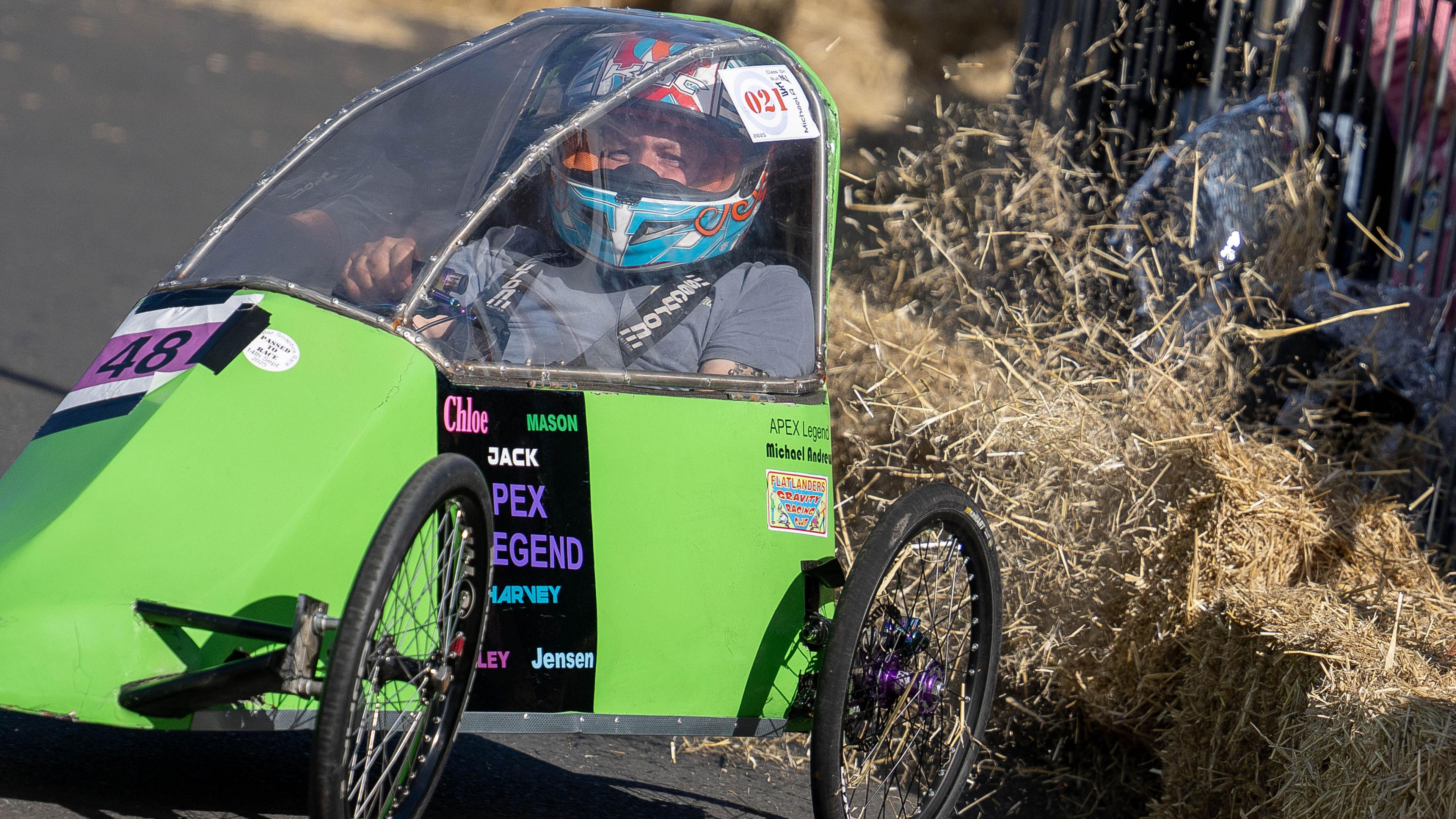 A small green painted kart with an entry number 48 on the front. Hay from a hay bale has been knocked into the air