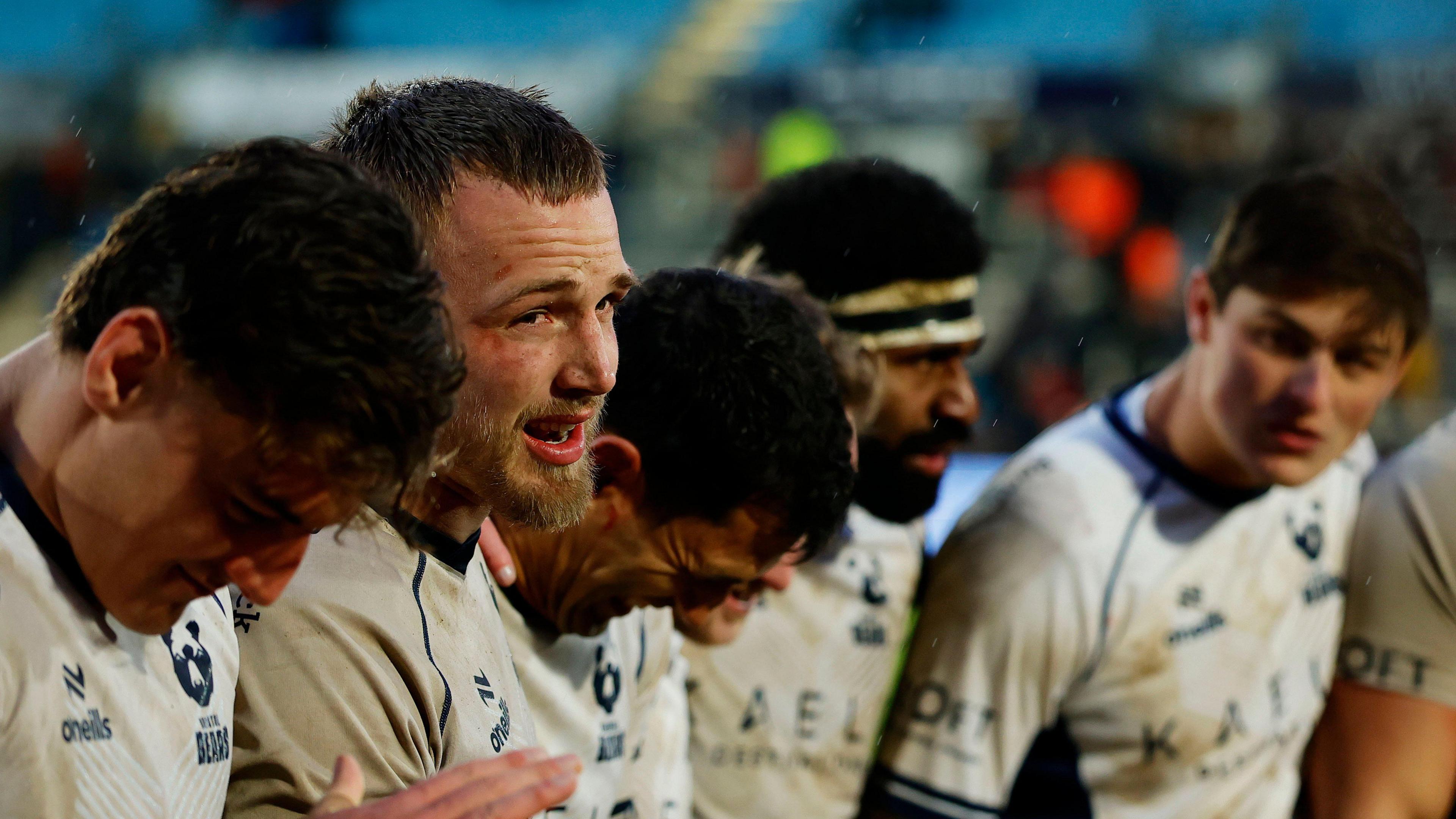 Fitz Harding (second left) speaks in a team huddle as players stand in a circle around him on the pitch