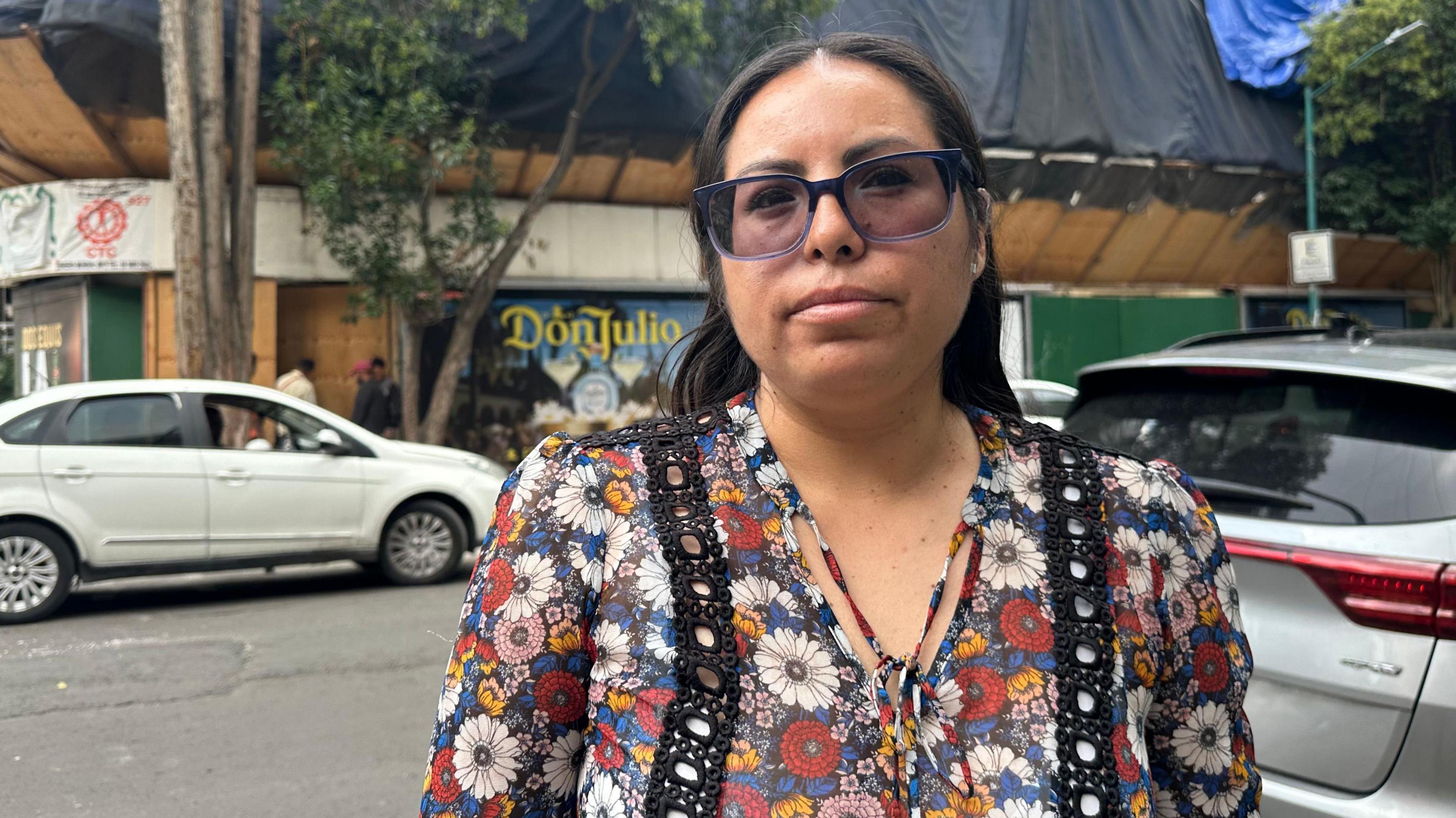 Erika Aguilar stands outside the apartment building where she and her family used to live on a street in central Mexico City