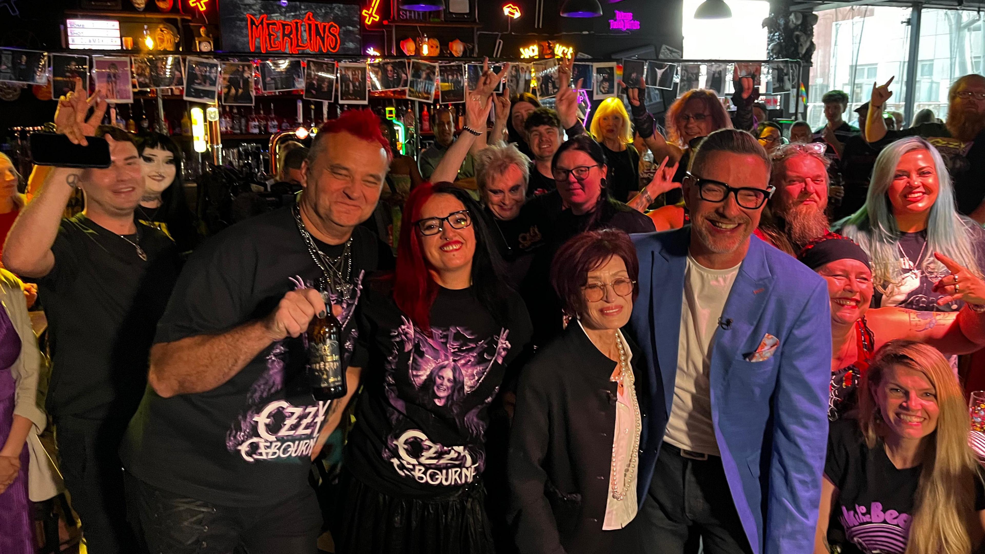 A crowd of people inside a bar looking towards the camera and smiling.