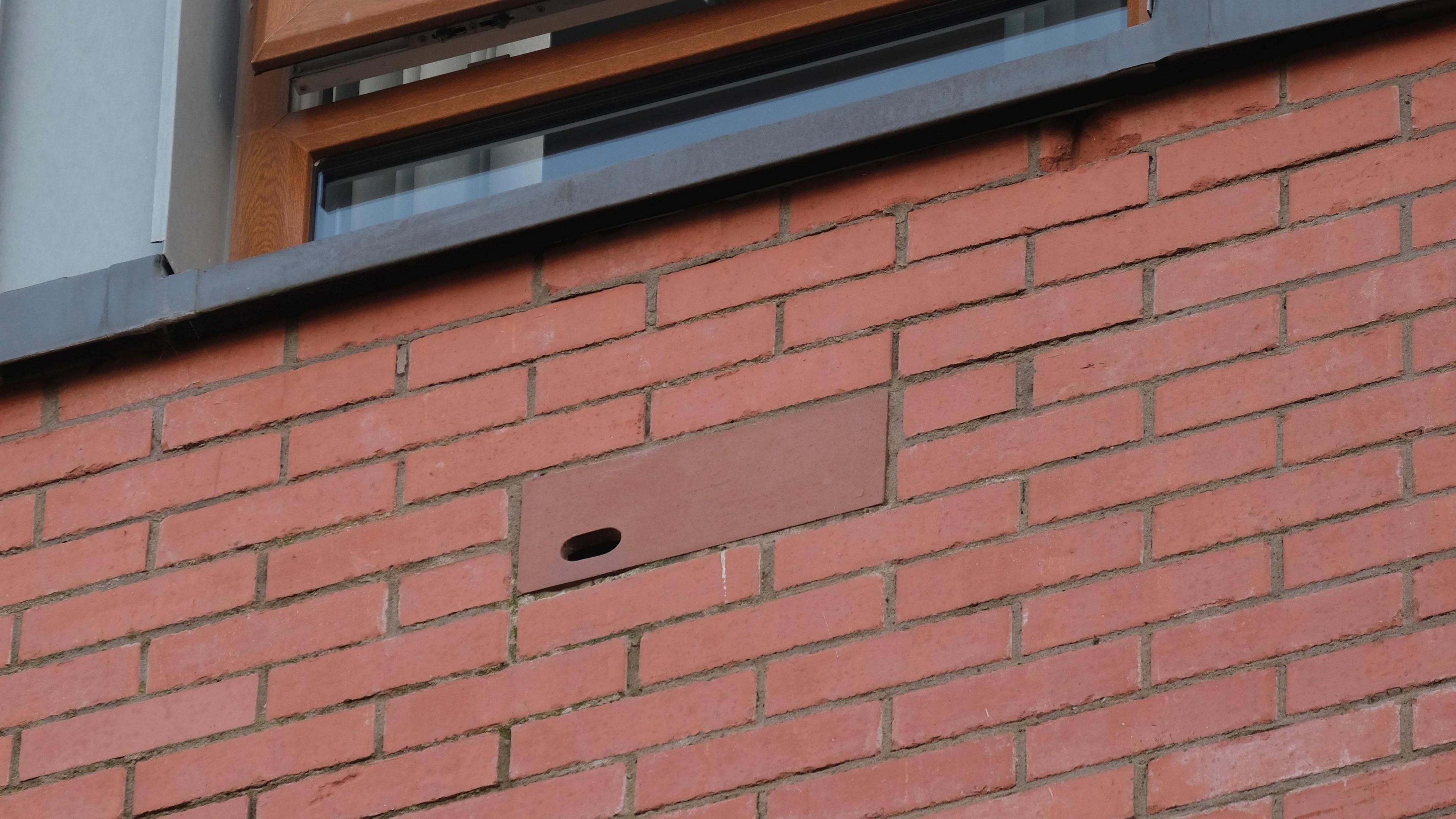 A red bricked building with a little hole in it 