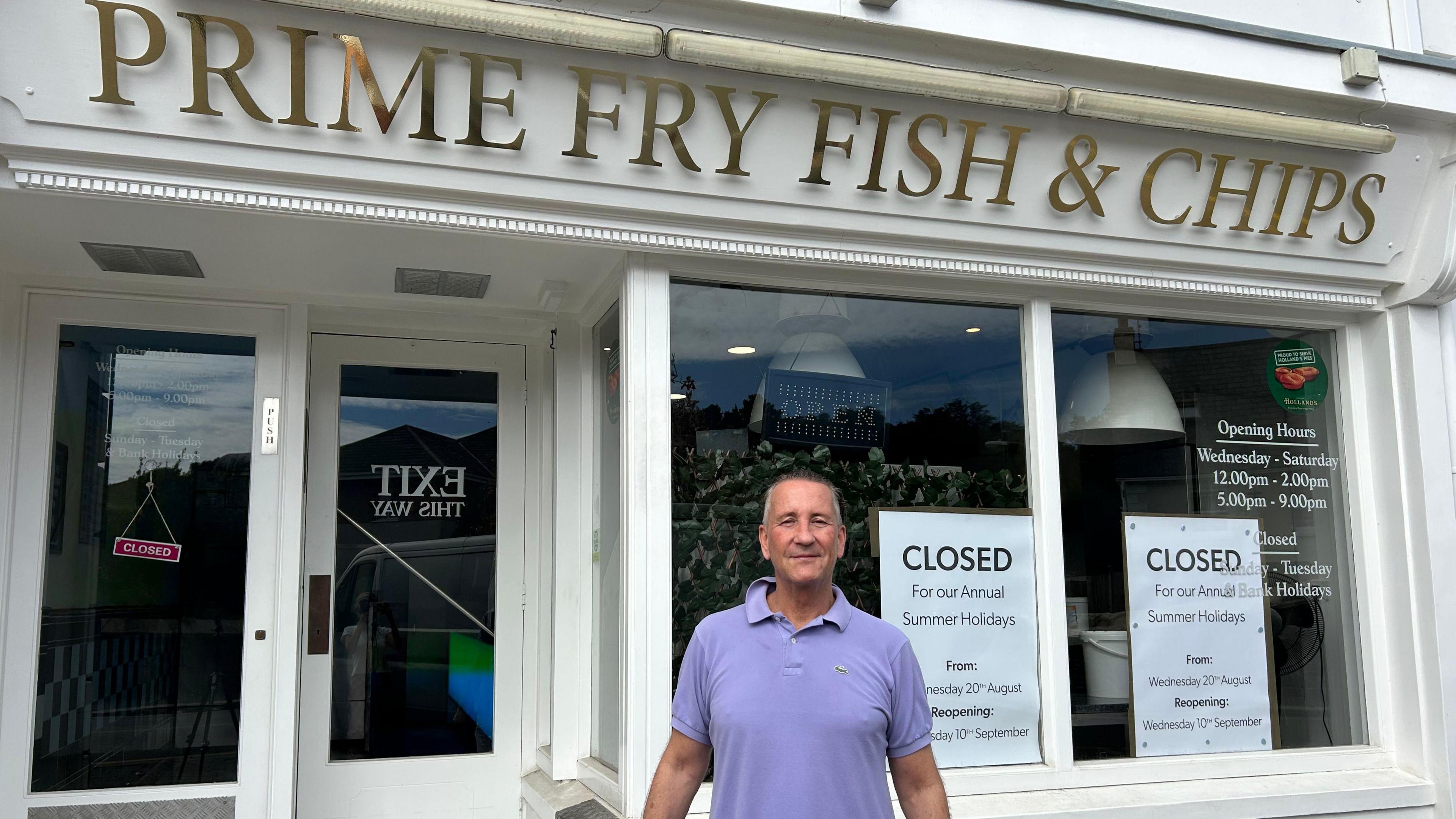 Tom Howell is stood in front of his shop Prime Fry Fish & Chips wearing a purple polo shirt.